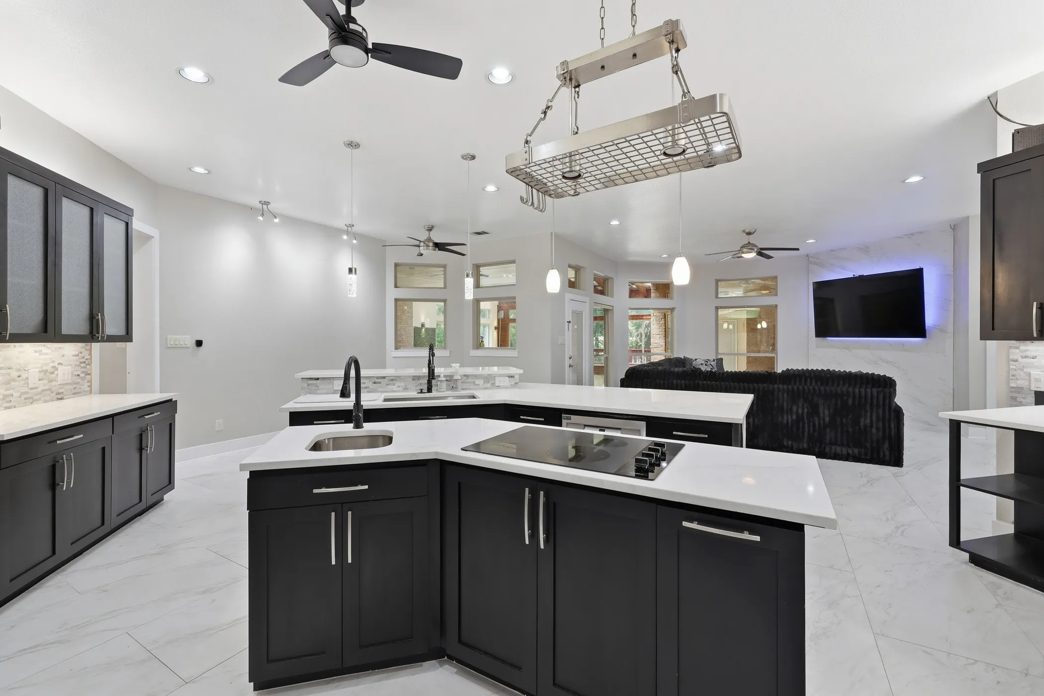 Open-concept kitchen featuring dark cabinetry, white countertops, tile flooring, and a built-in cooktop
