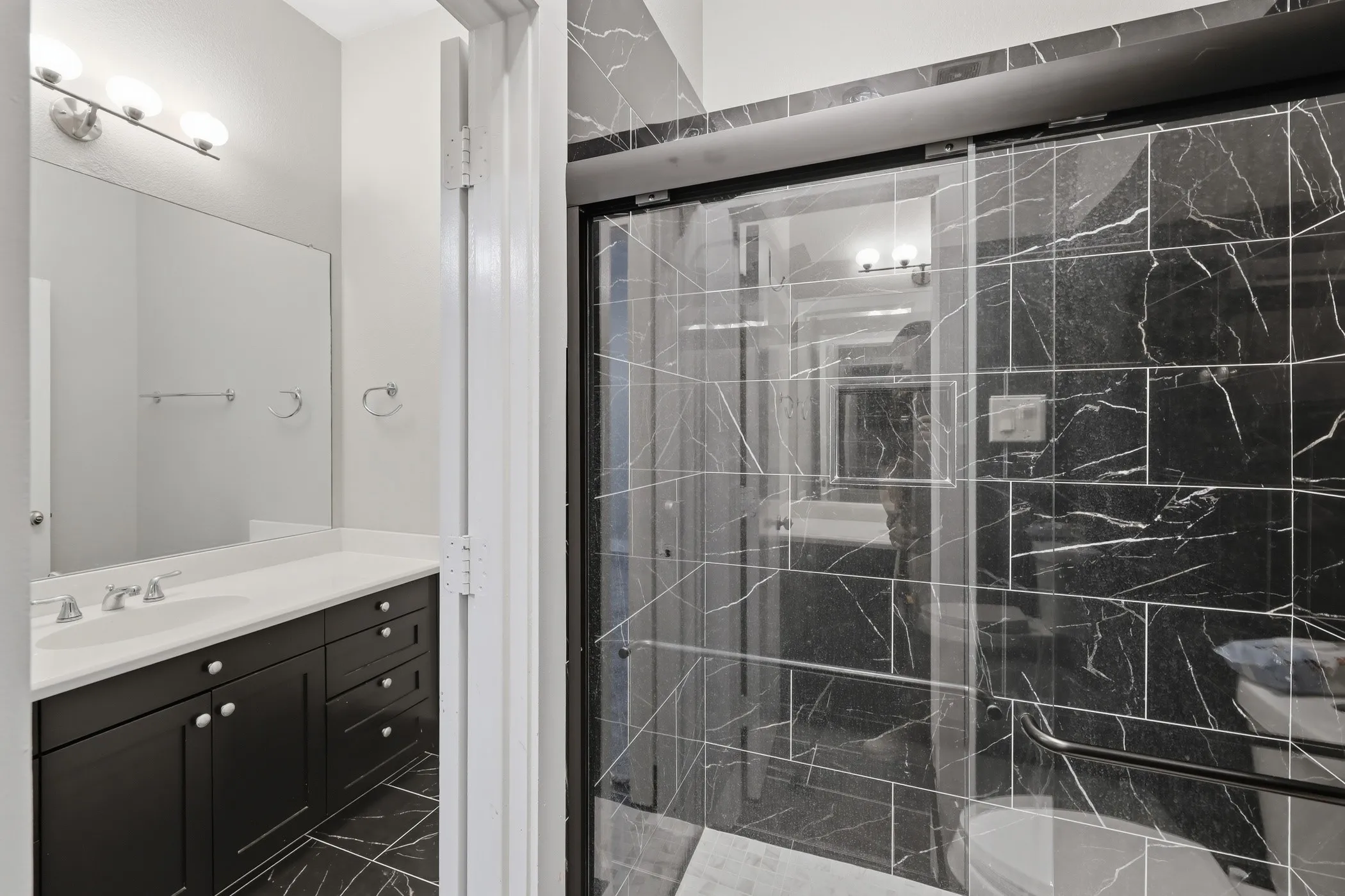 Black marble-look tiled shower with glass enclosure
