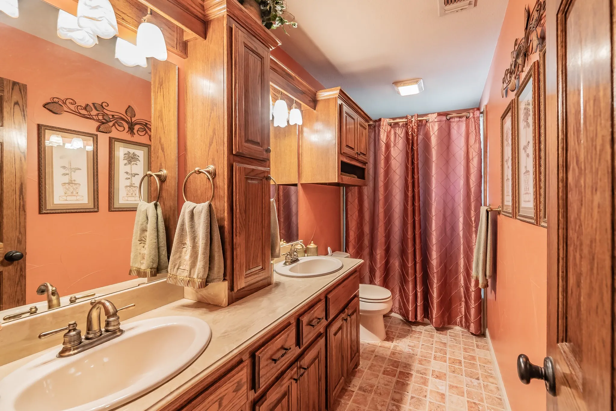 Full bath with toilet and double vanity, custom cabinets