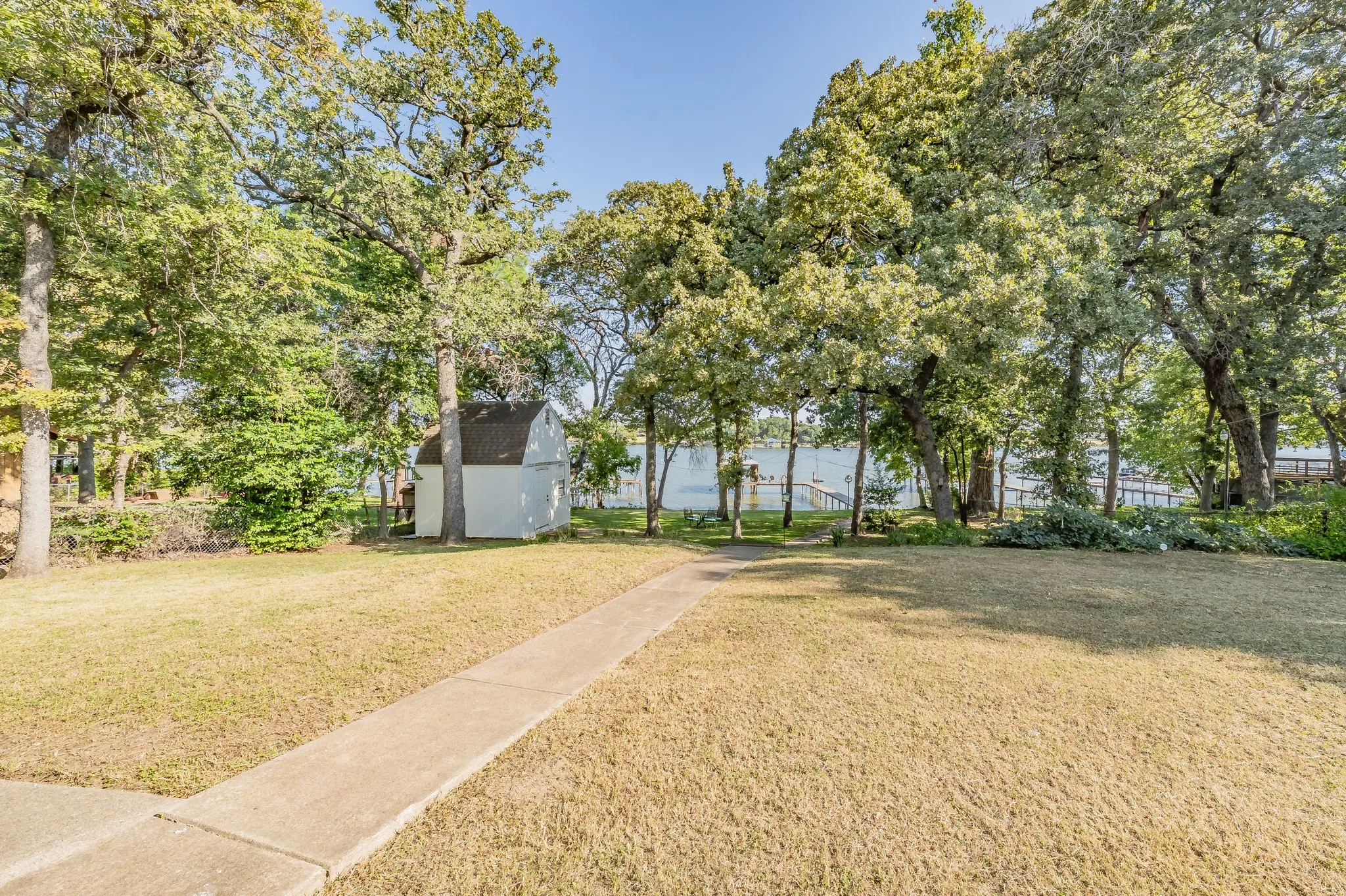 View of green lawn with an outdoor structure and a water view