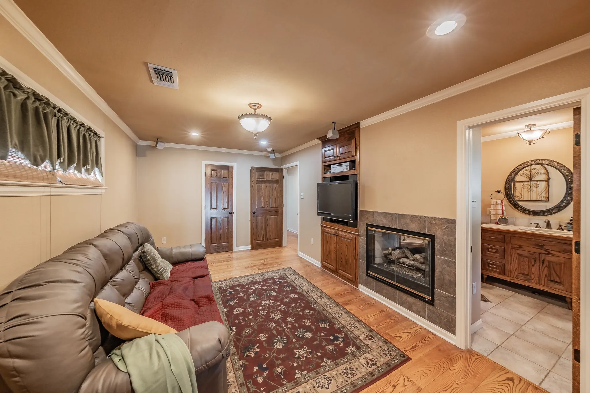Living room with light wood-type real wood flooring, custom built in, double sided gap, crown molding, and recessed lighting