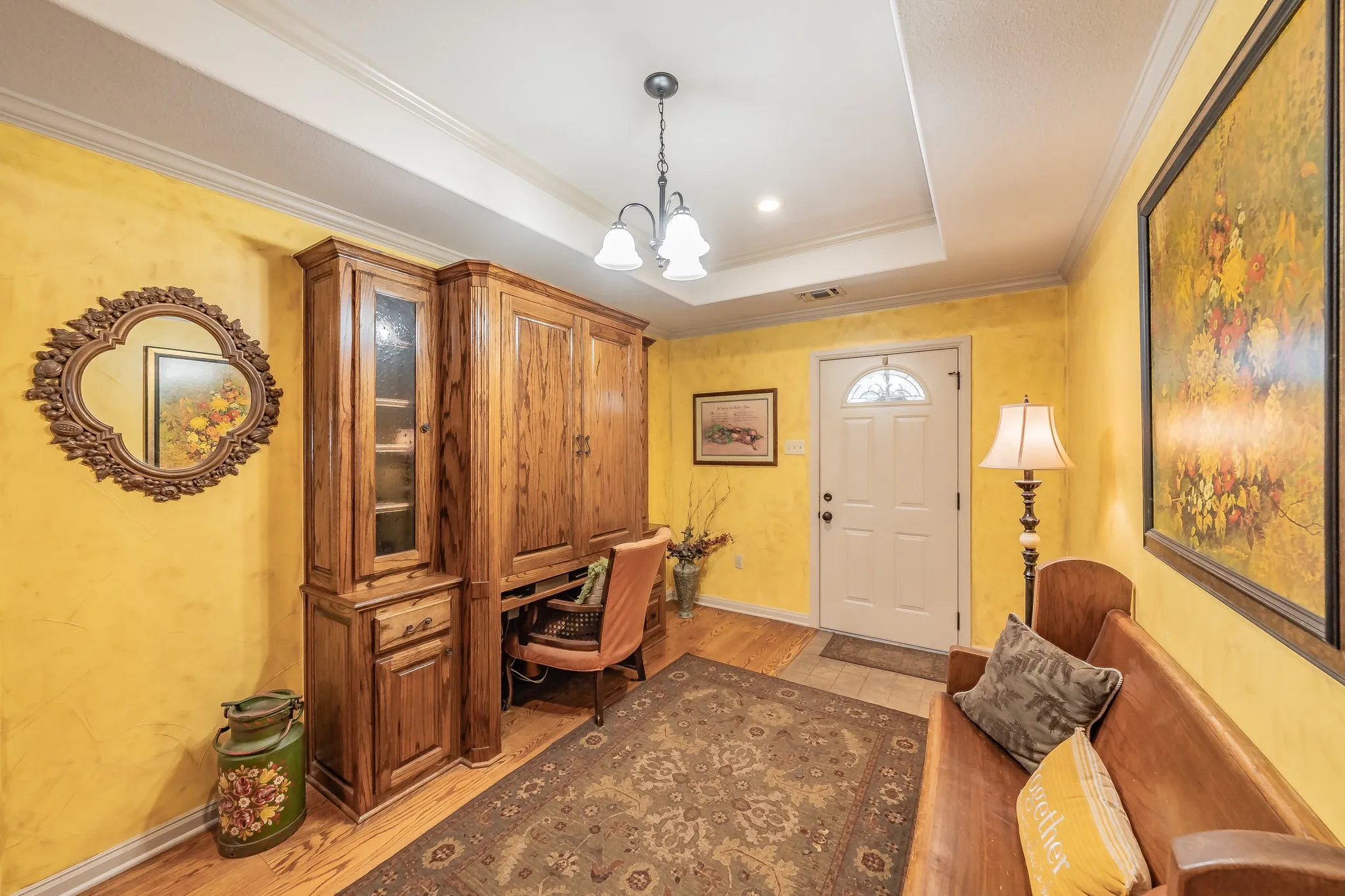 Home office with crown molding, a tray ceiling, light real wood-style flooring, and a chandelier