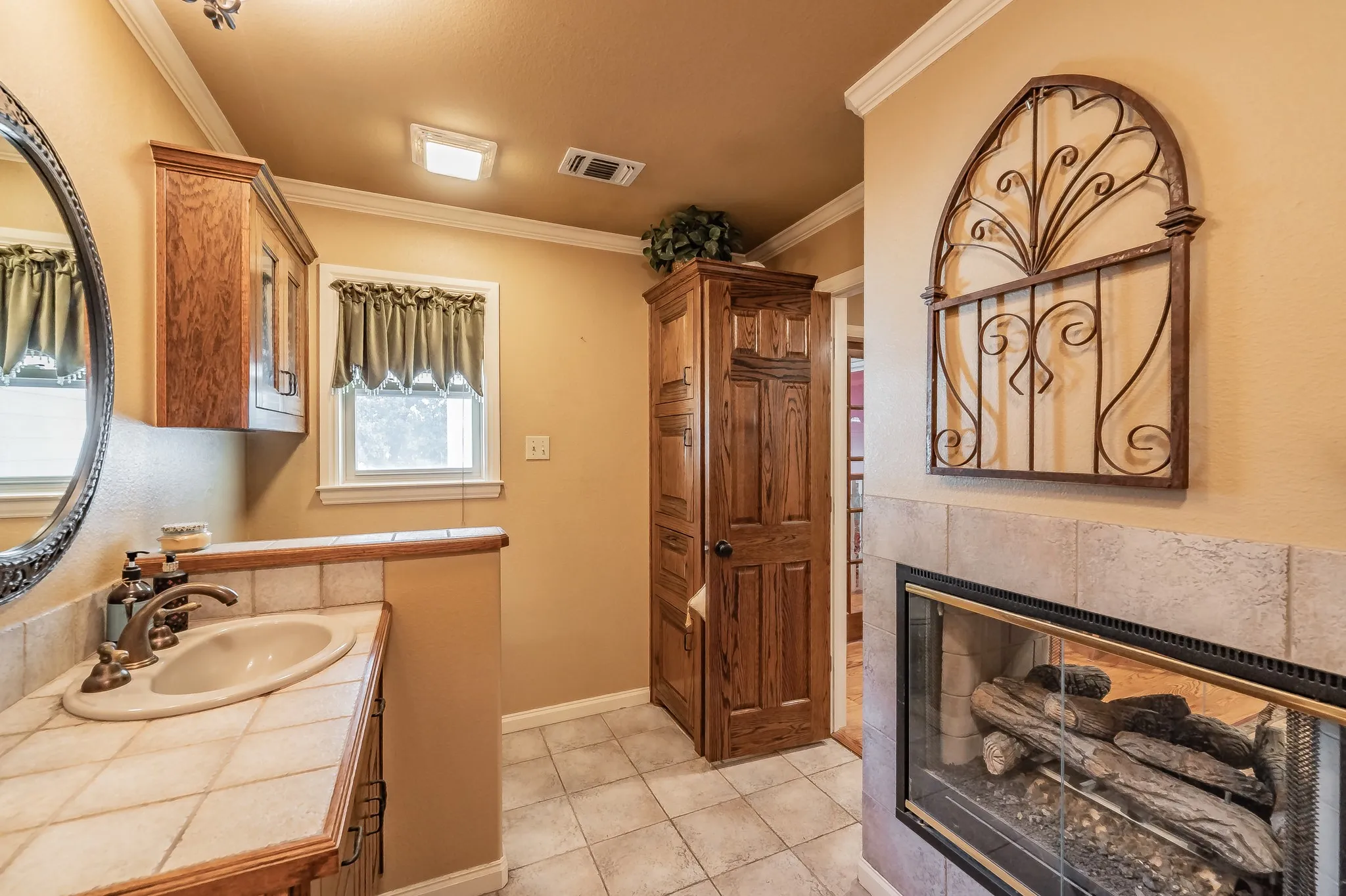 Bathroom with vanity, light tile patterned flooring, a fireplace, and crown molding
