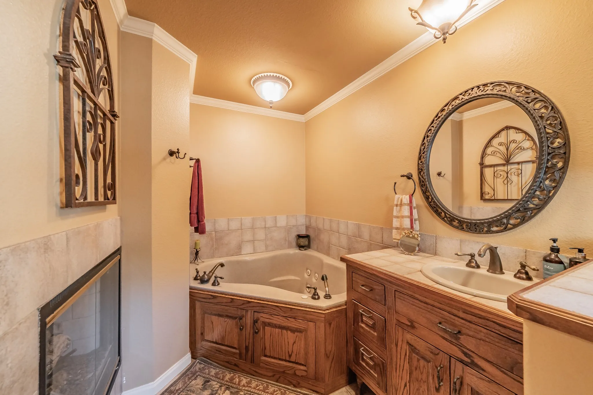 Full bathroom with ornamental molding, vanity, a garden tub, and a glass covered fireplace
