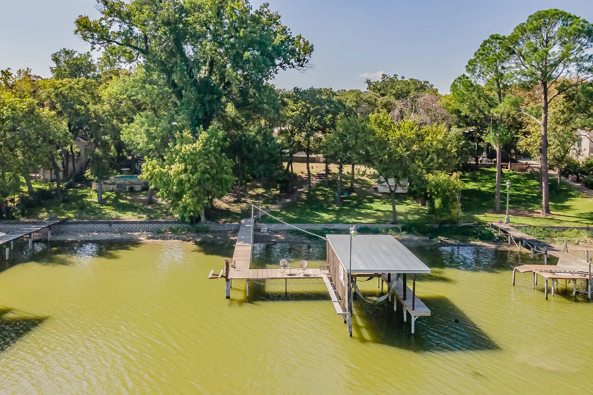 Dock area featuring view of scattered trees, a water view, and boat lift