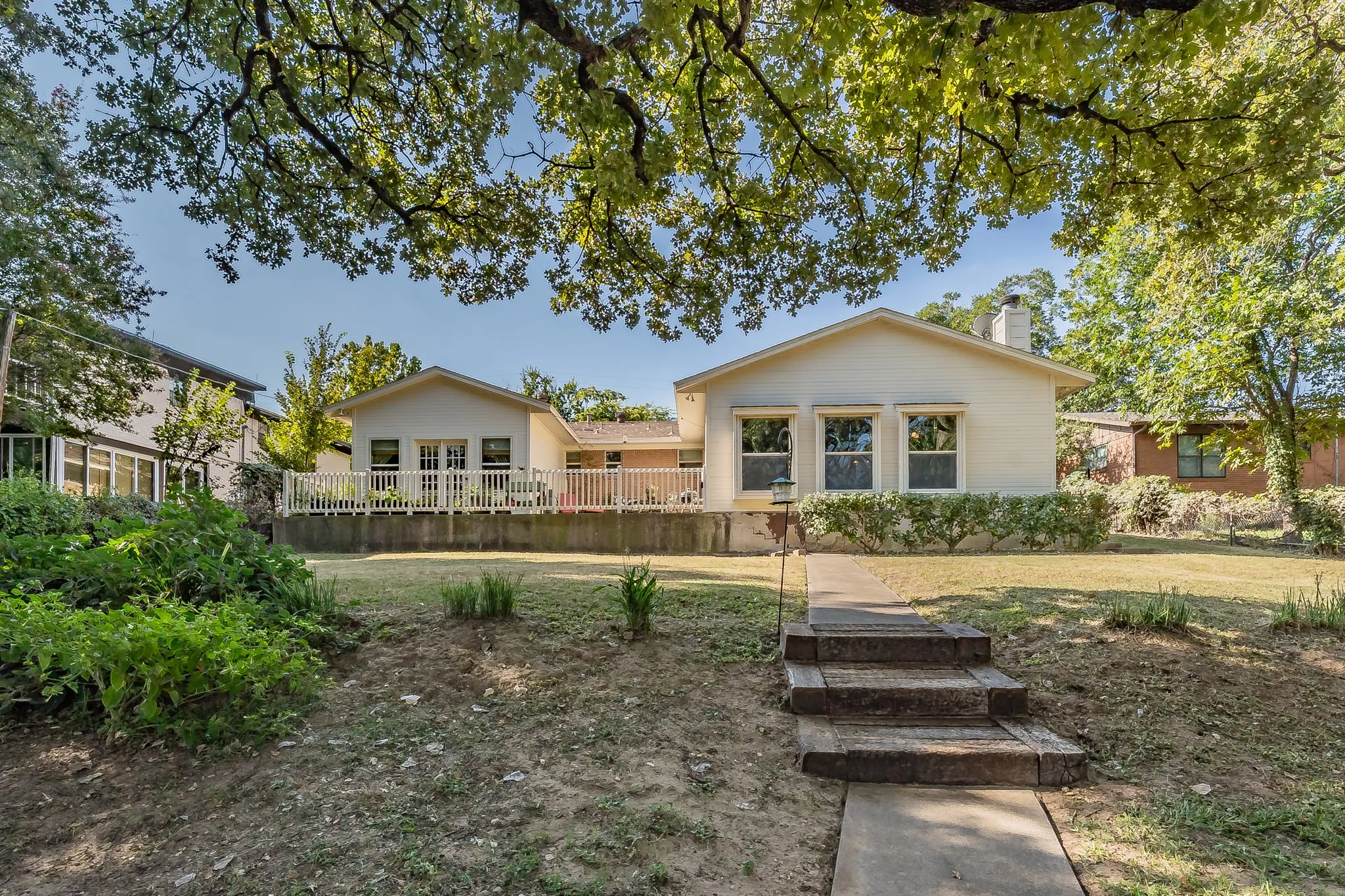 Rear view of property featuring a chimney, patios, large windows overlooking the lake.