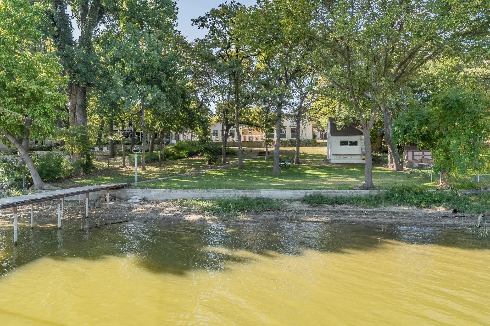 Dock area featuring a water view, a lawn, and view of scattered trees