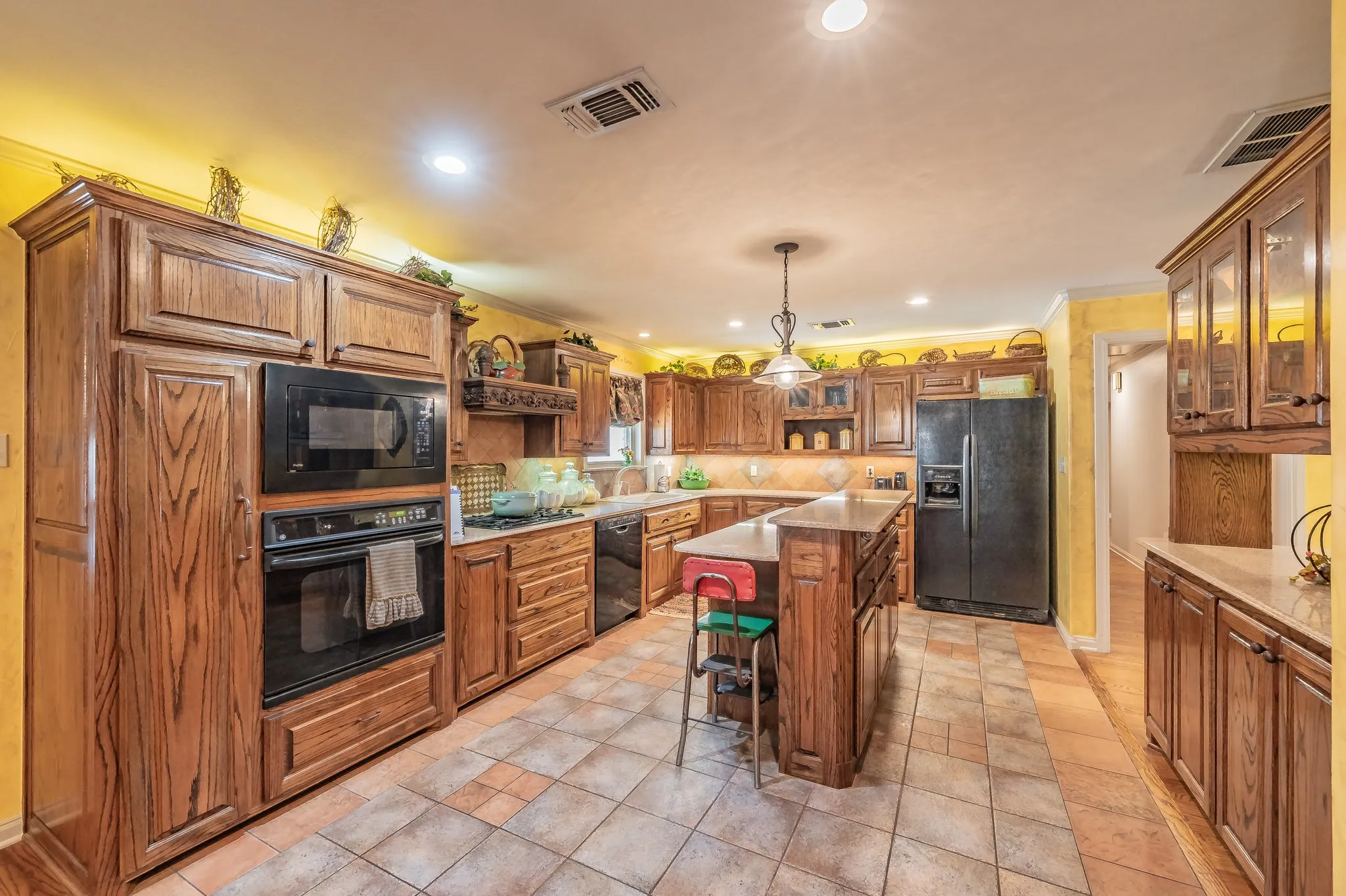 Kitchen with glass insert cabinets, a kitchen breakfast bar, black appliances, custom cabinetry, and tasteful backsplash, and multiple built ins