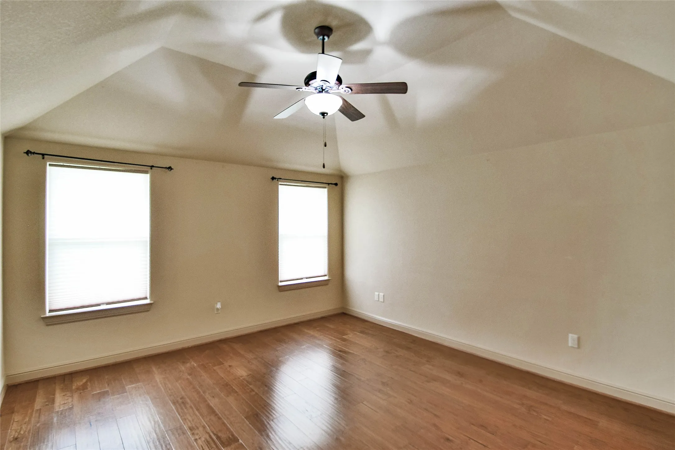 Primary bedroom with wood flooring, ceiling fan, tray ceiling