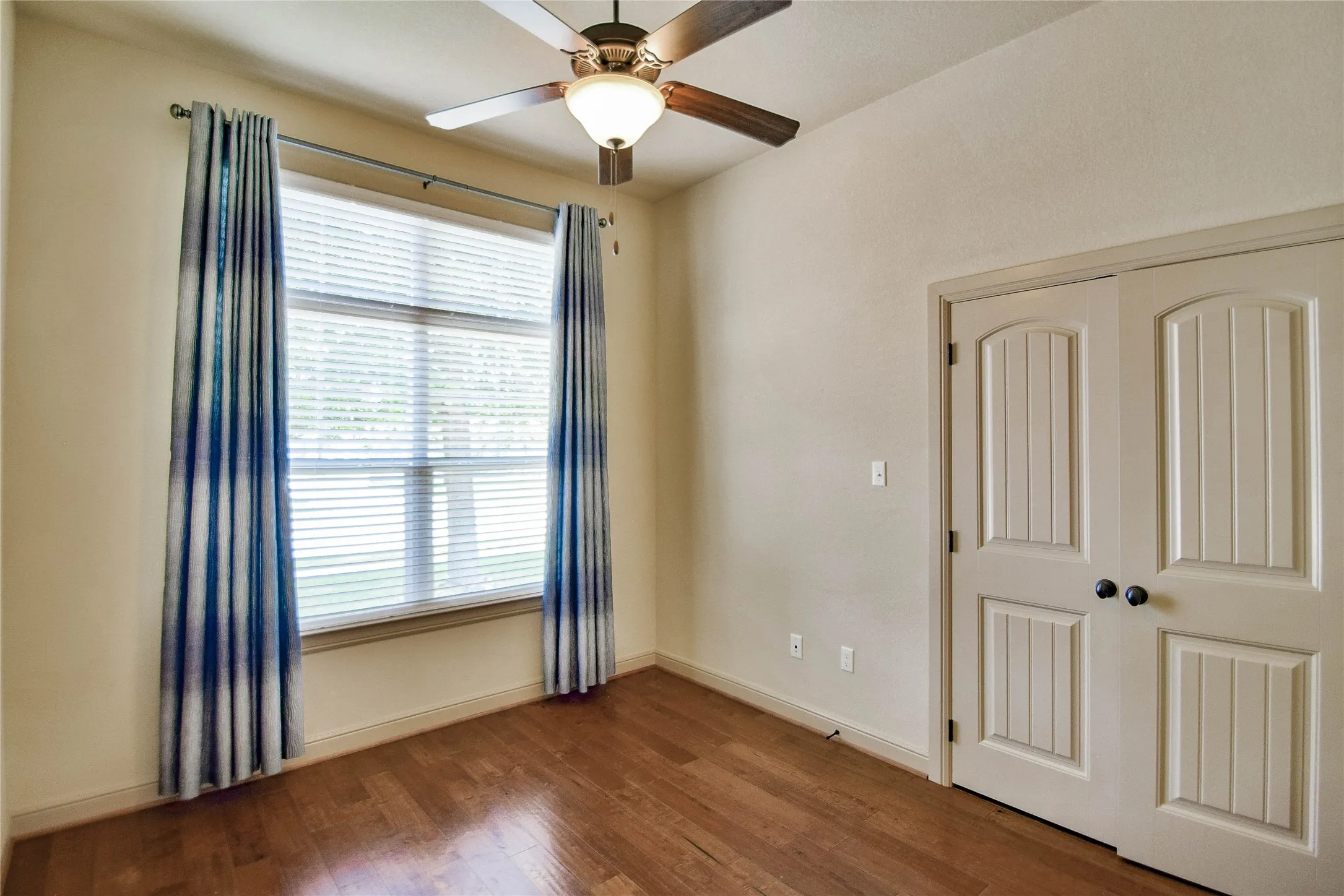 2nd bedroom with wood flooring, ceiling fan