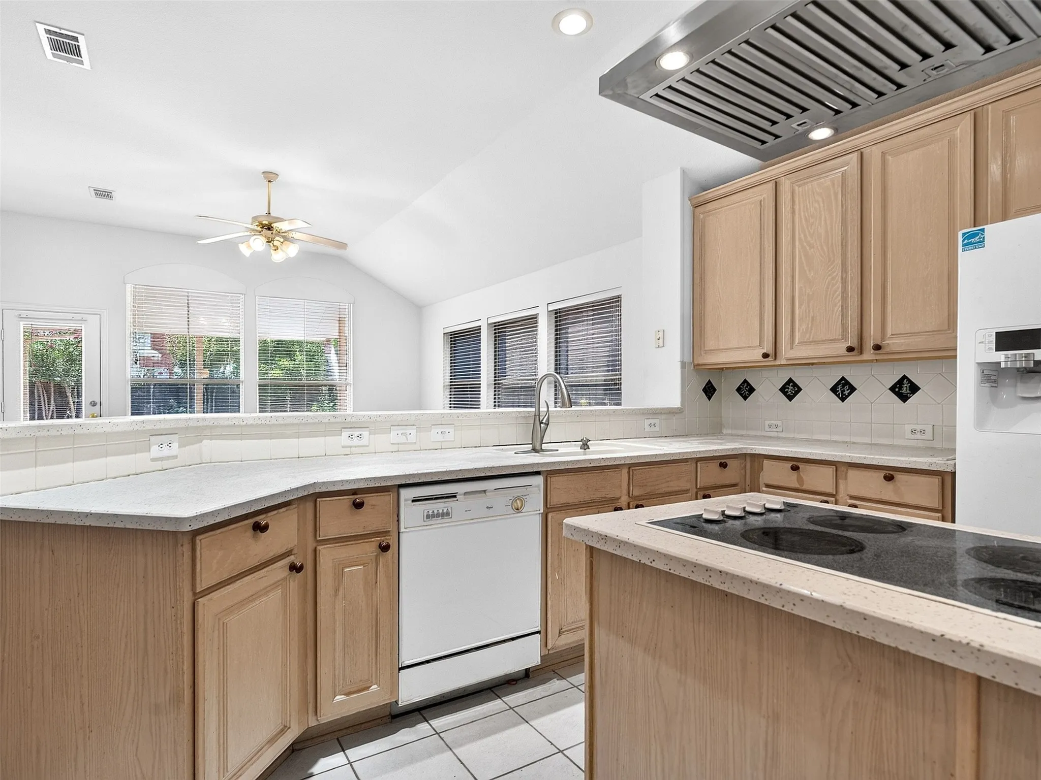 Kitchen featuring light wood cabinetry, white tile flooring, recessed lighting, and an island with an electric cooktop