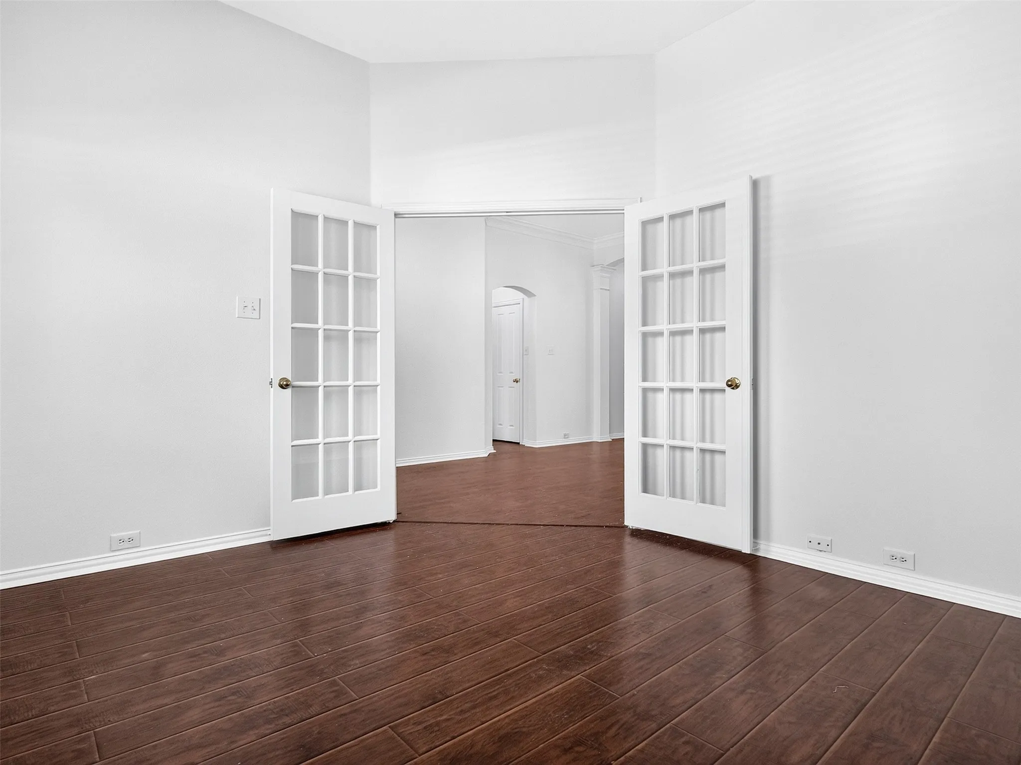 Rich wood-finish flooring with white baseboards and neutral wall tones