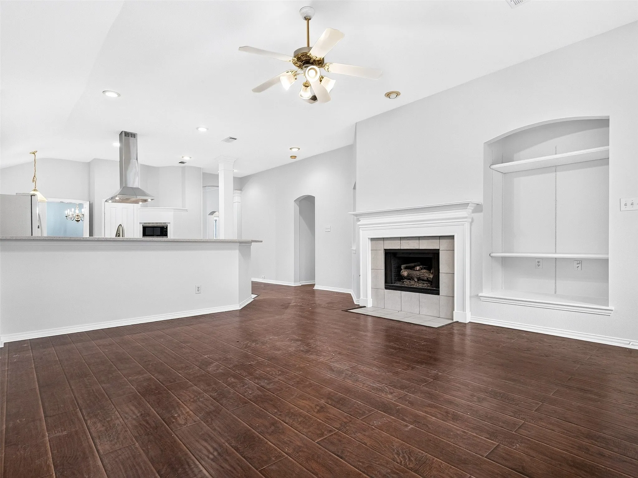 Spacious interior with wood-finish flooring, a ceiling fan, and recessed lighting