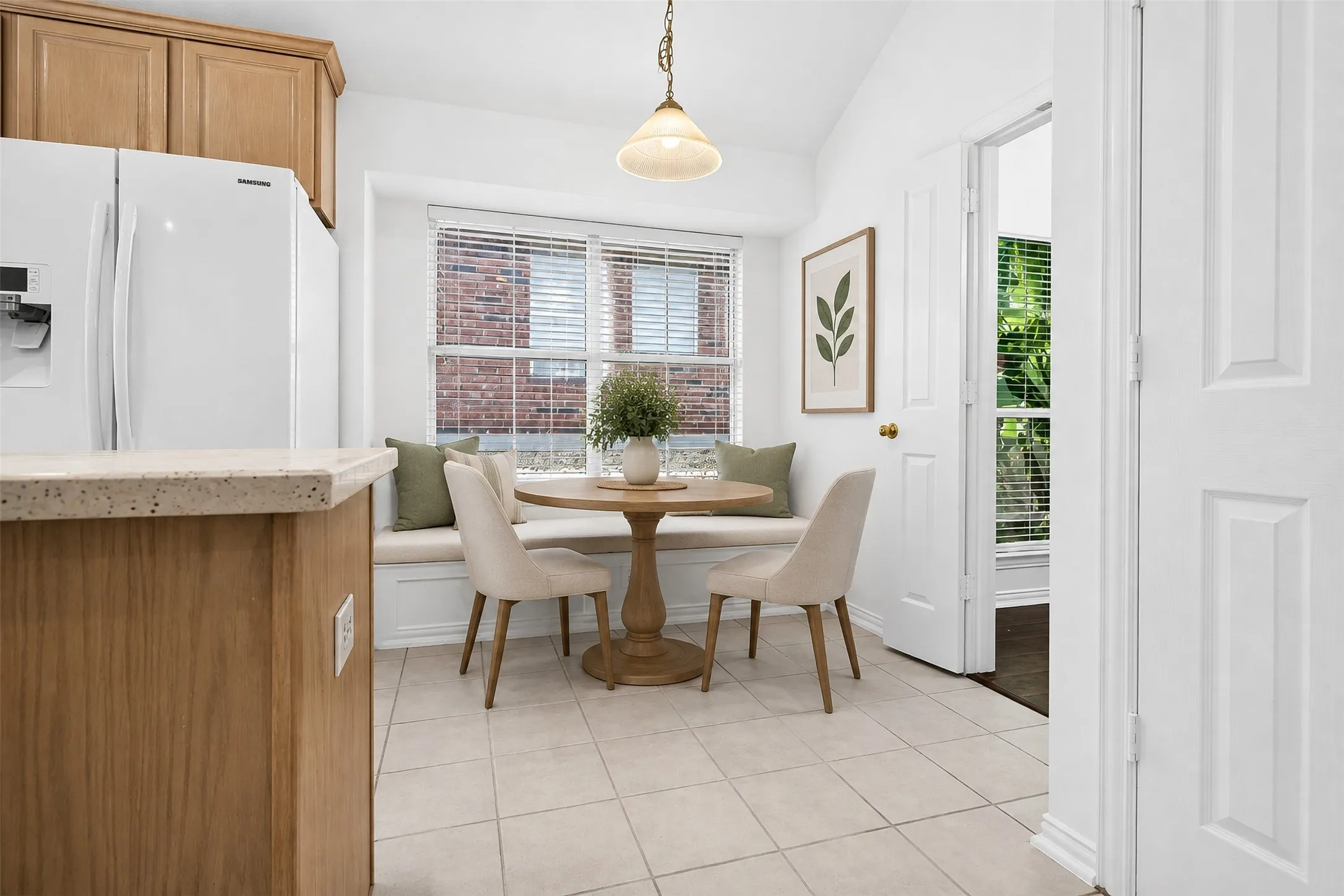 Built-in window seating, tile flooring, light wood-finish cabinetry, and a light-toned countertop