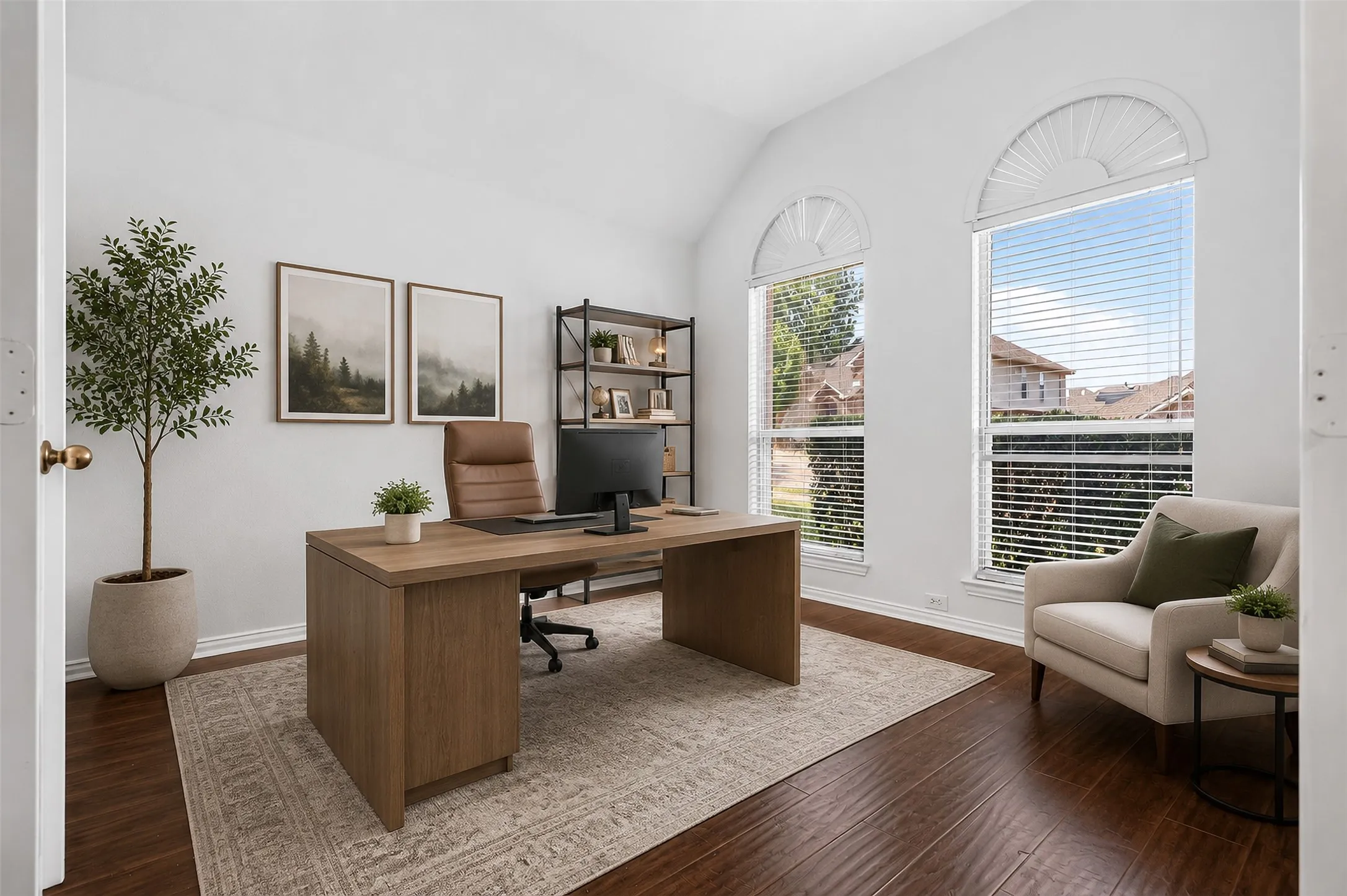 Vaulted ceilings, wood-finish flooring, and two large arched windows with blinds define this bright room