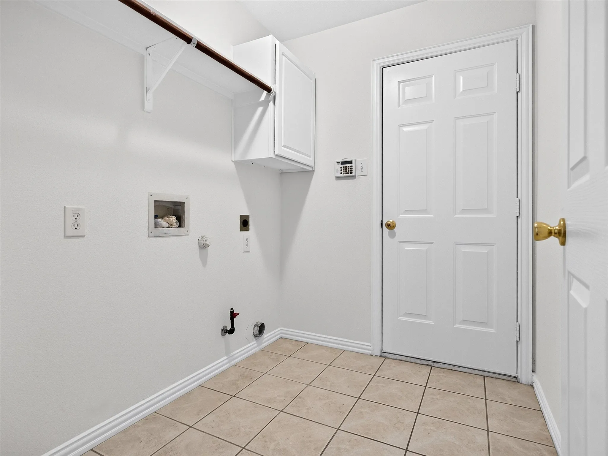 Tile flooring, white cabinetry, built-in shelving with hanging rod, and white paneled doors