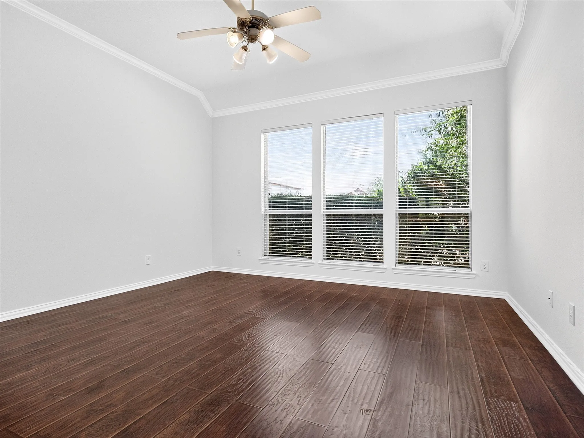 Vaulted ceiling with crown molding, wood-finish flooring, and a ceiling fan with integrated lighting