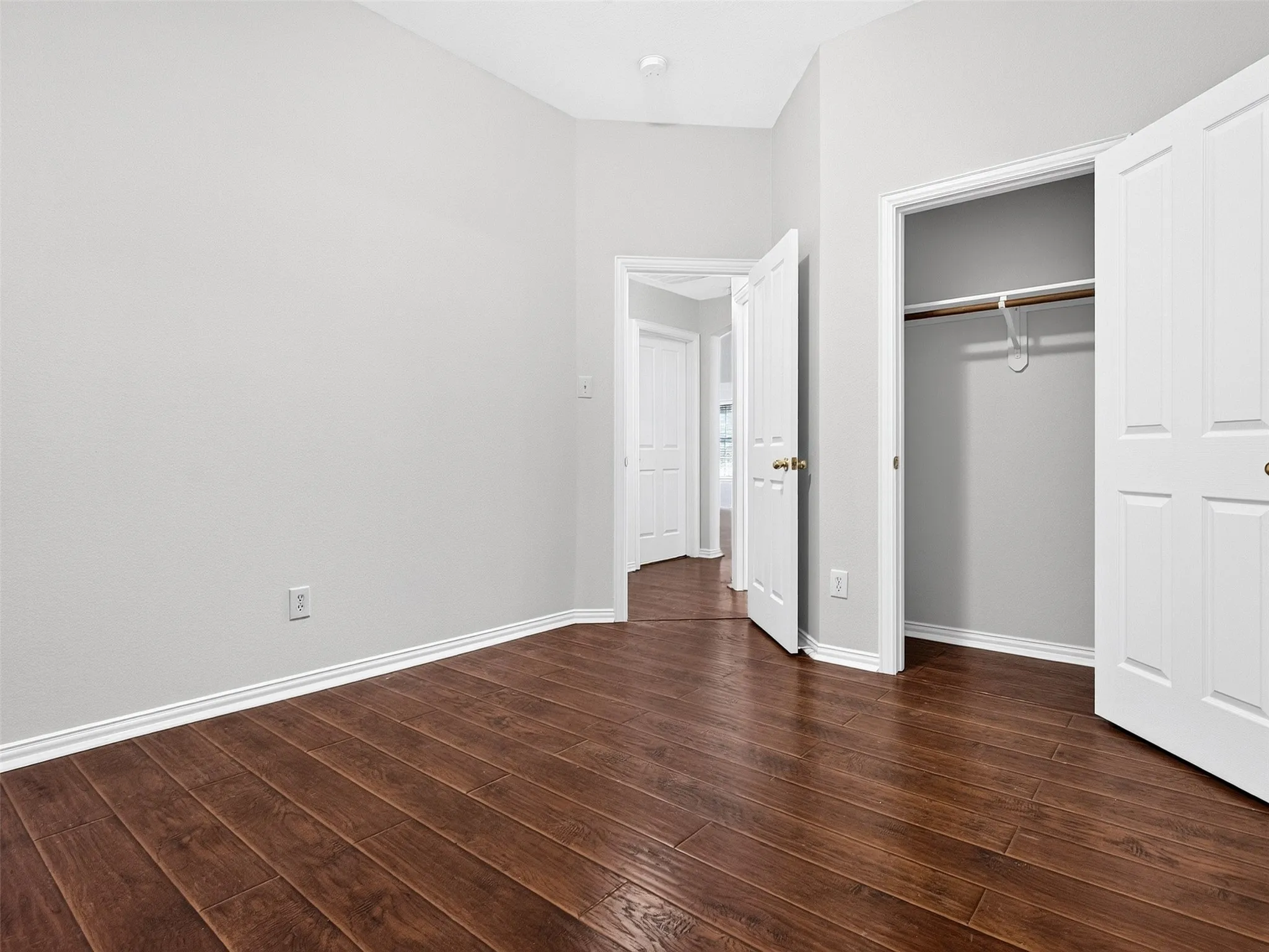 Wood-finish flooring, white wall paint, white trim, interior closet, and a hallway