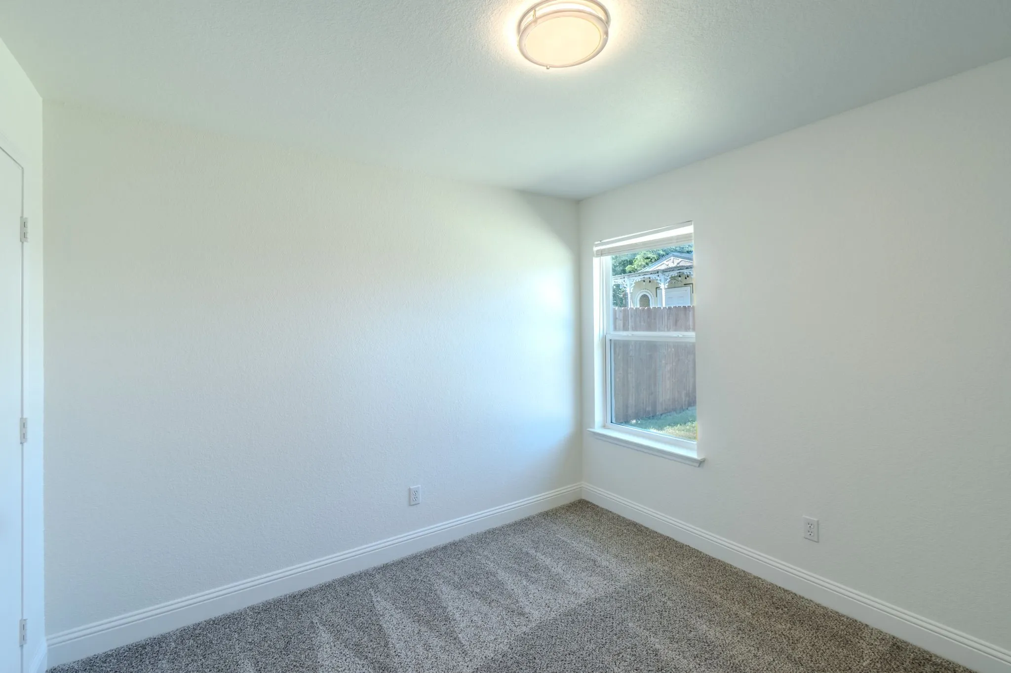 Neutral wall paint, window, wall-to-wall carpeting, and a flush mount ceiling light