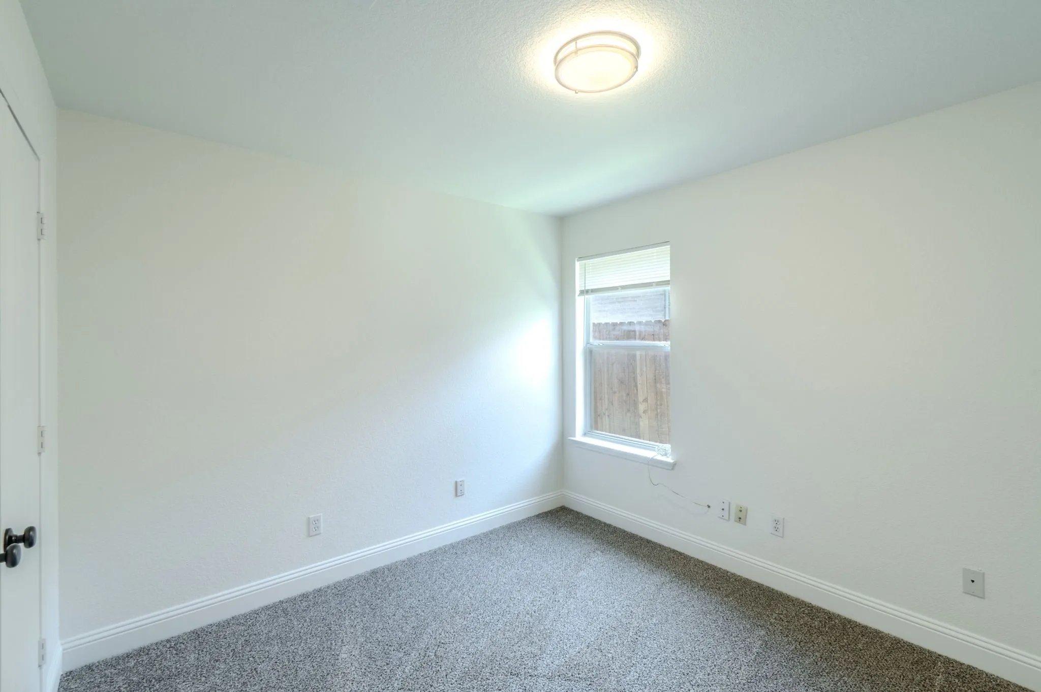 Neutral wall paint, window, wall-to-wall carpeting, and a flush mount ceiling light