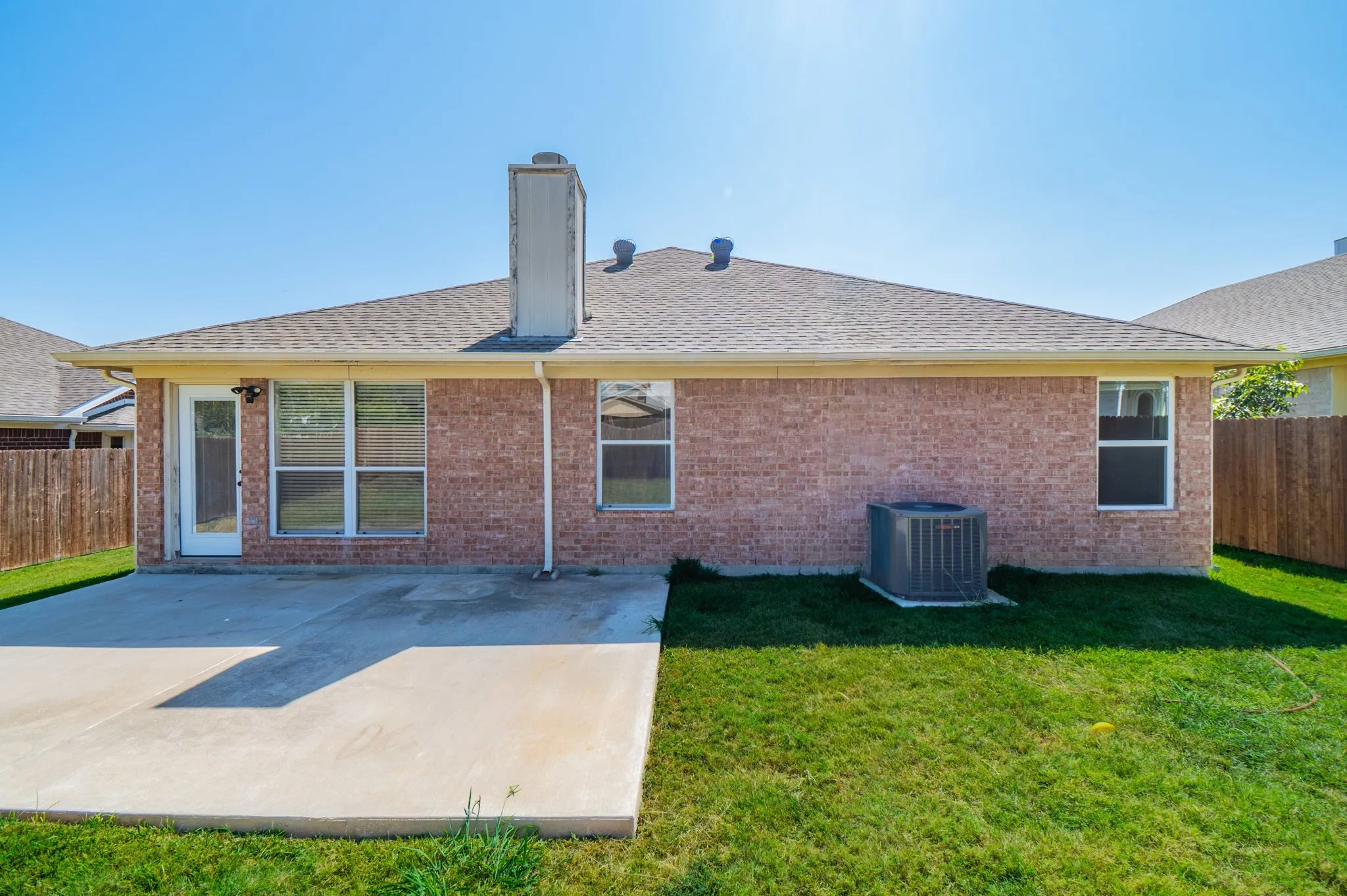 Brick exterior with a gabled roof and a concrete patio