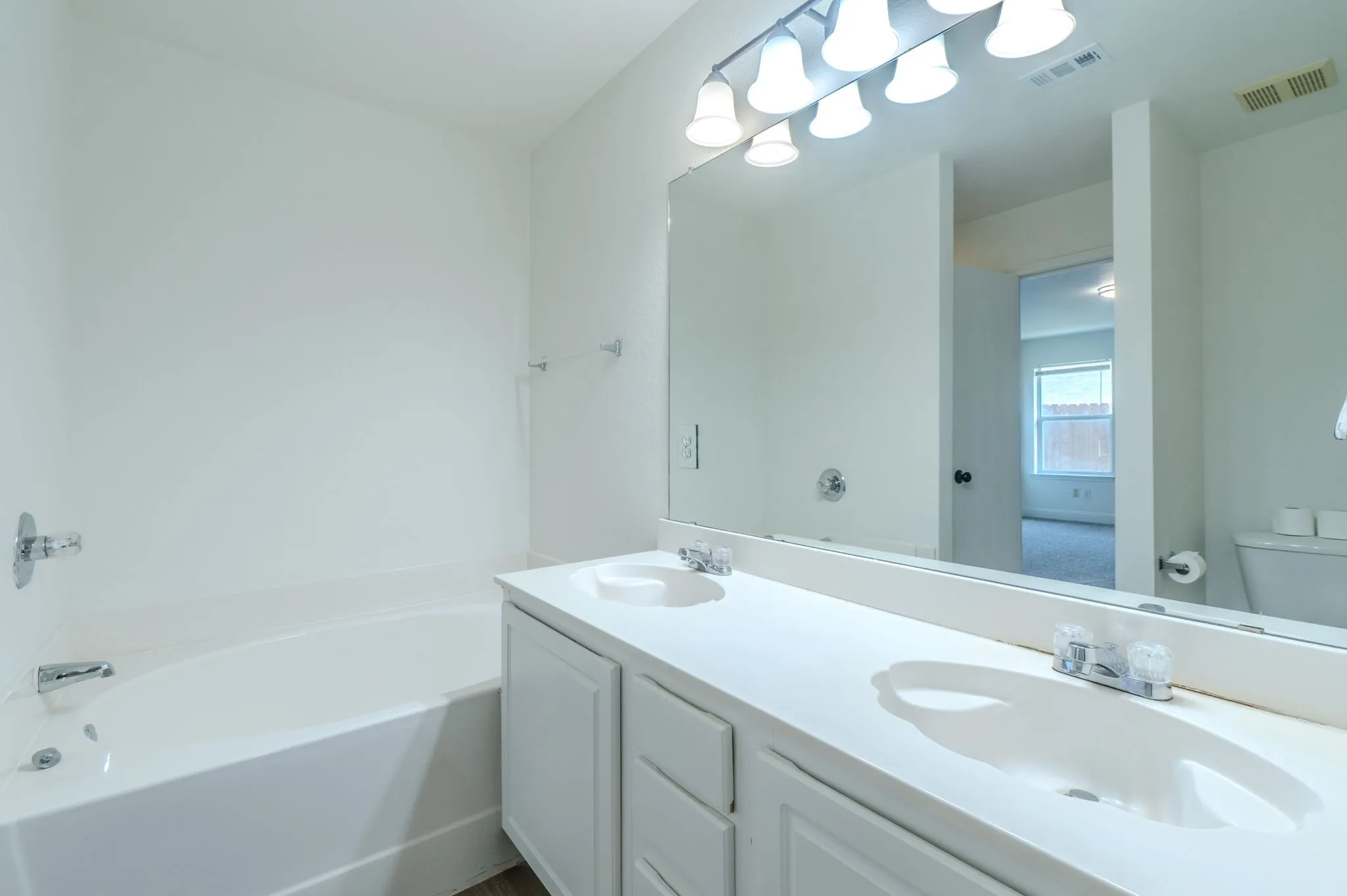 Dual vanity with white cabinetry, integrated sinks, white countertop, and chrome fixtures