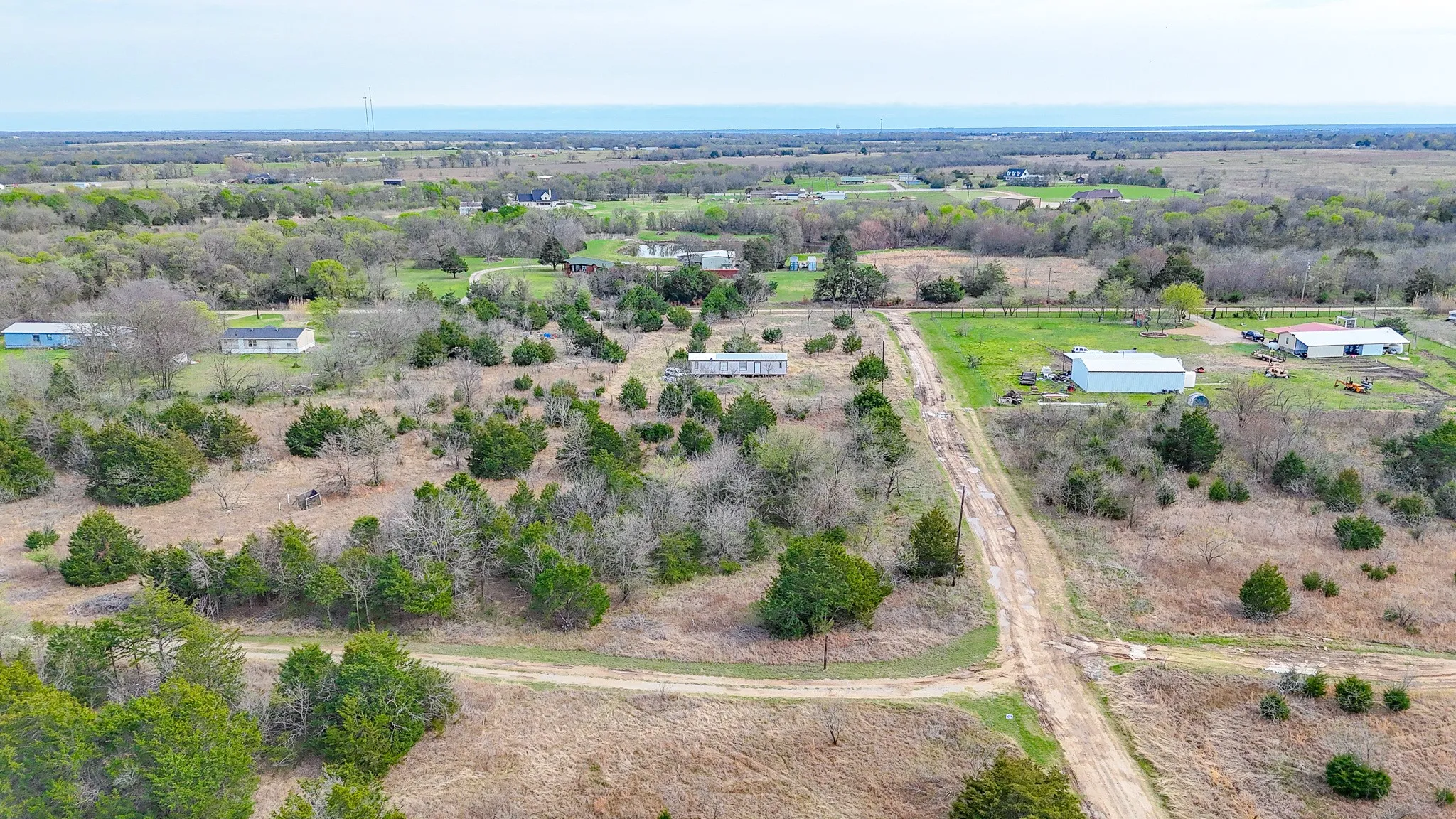 Expansive acreage featuring abundant mature trees and multiple structures