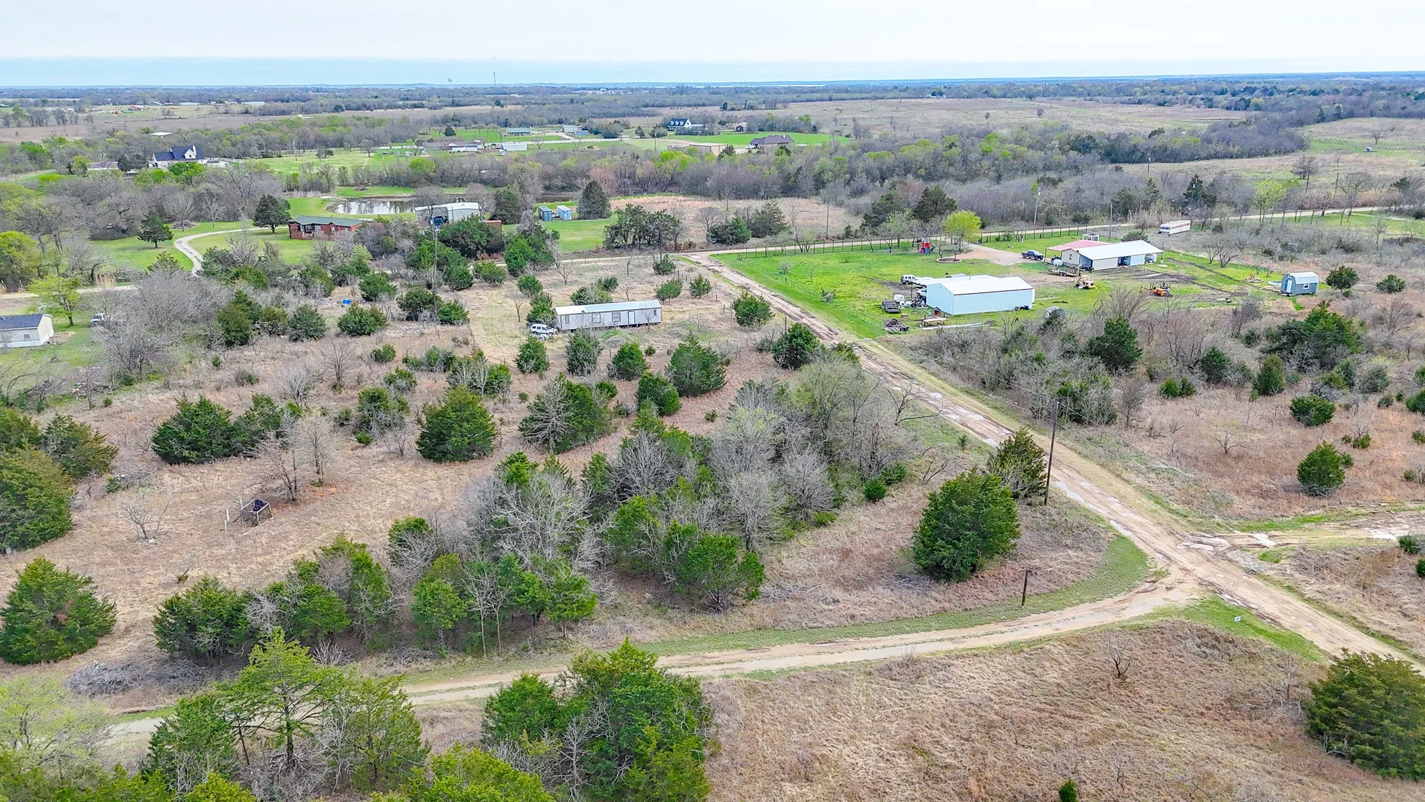 Expansive land featuring natural landscaping, mature trees, and unpaved roads