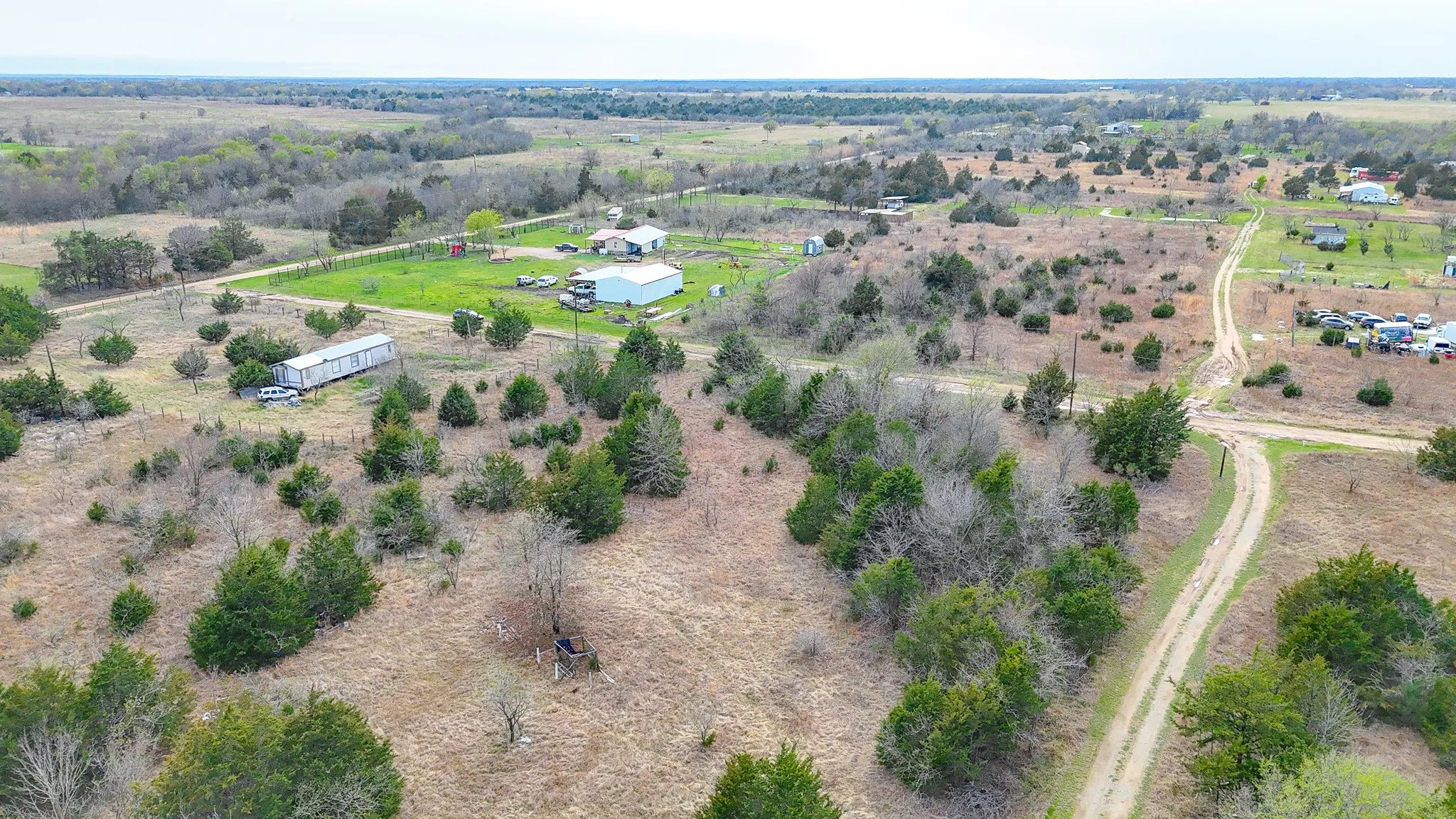 Expansive acreage featuring established trees, natural terrain, and a visible dirt road