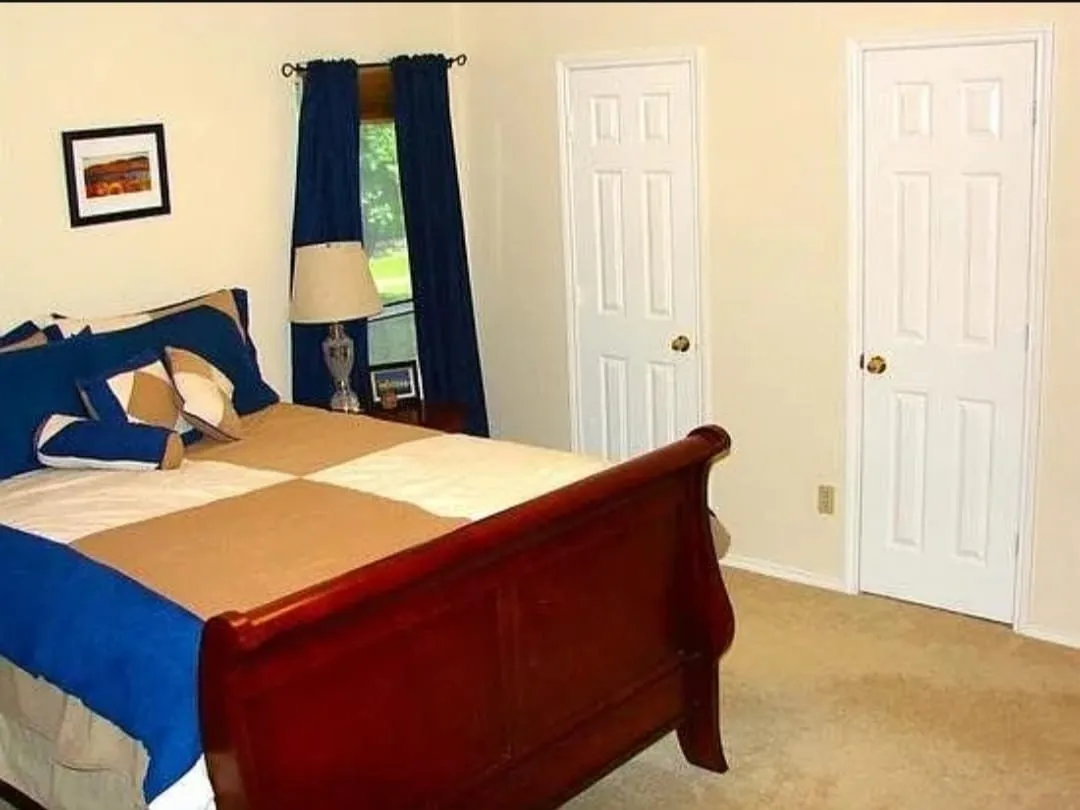 Neutral tone wall paint, light neutral carpet, white paneled doors, and a window with trim