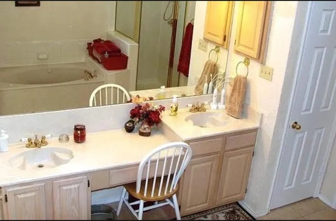 Dual vanity with integrated sinks, light wood-finish cabinetry, and a full-width mirror