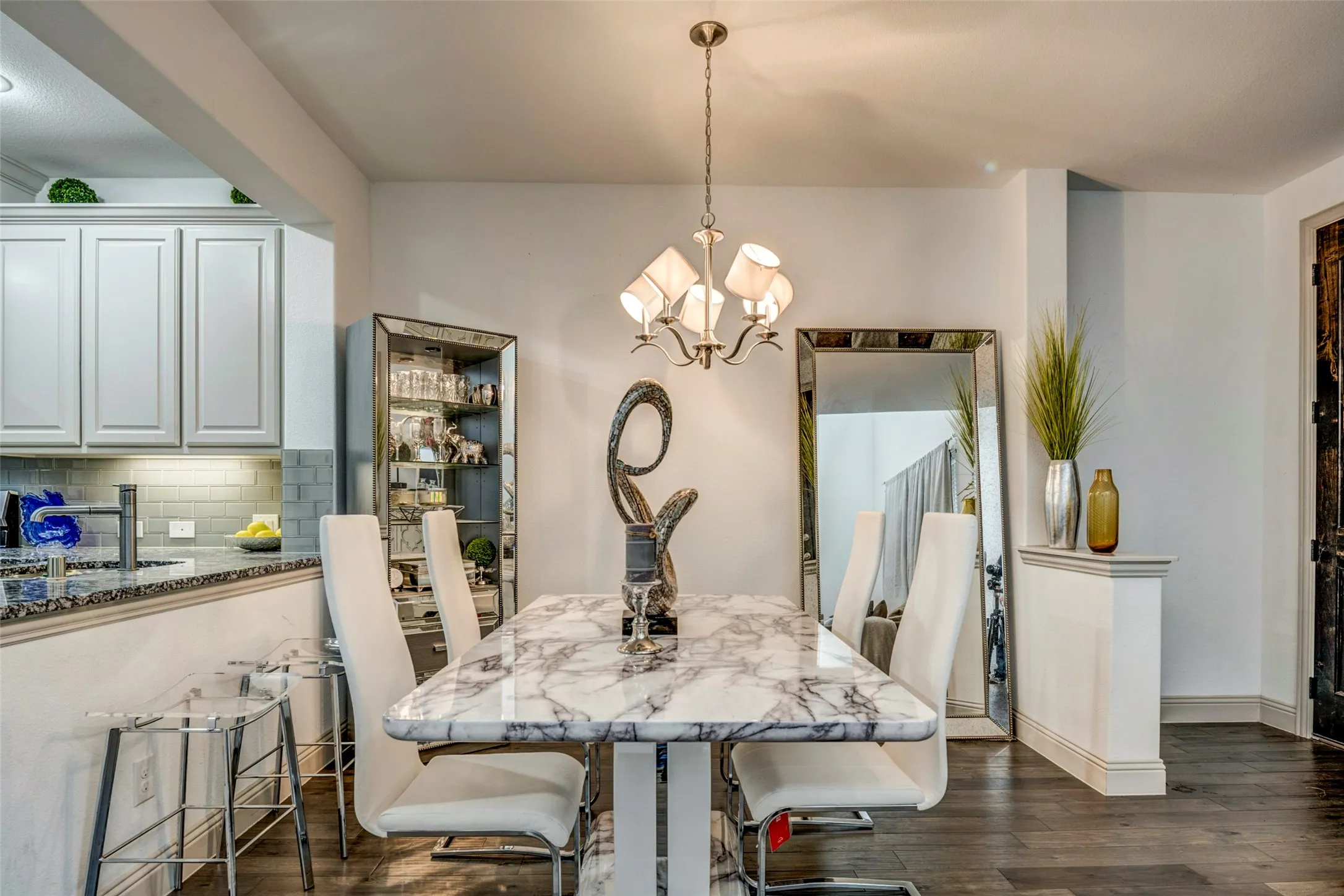 Dining area featuring dark wood-finish flooring, a contemporary chandelier, and a decorative wall mirror