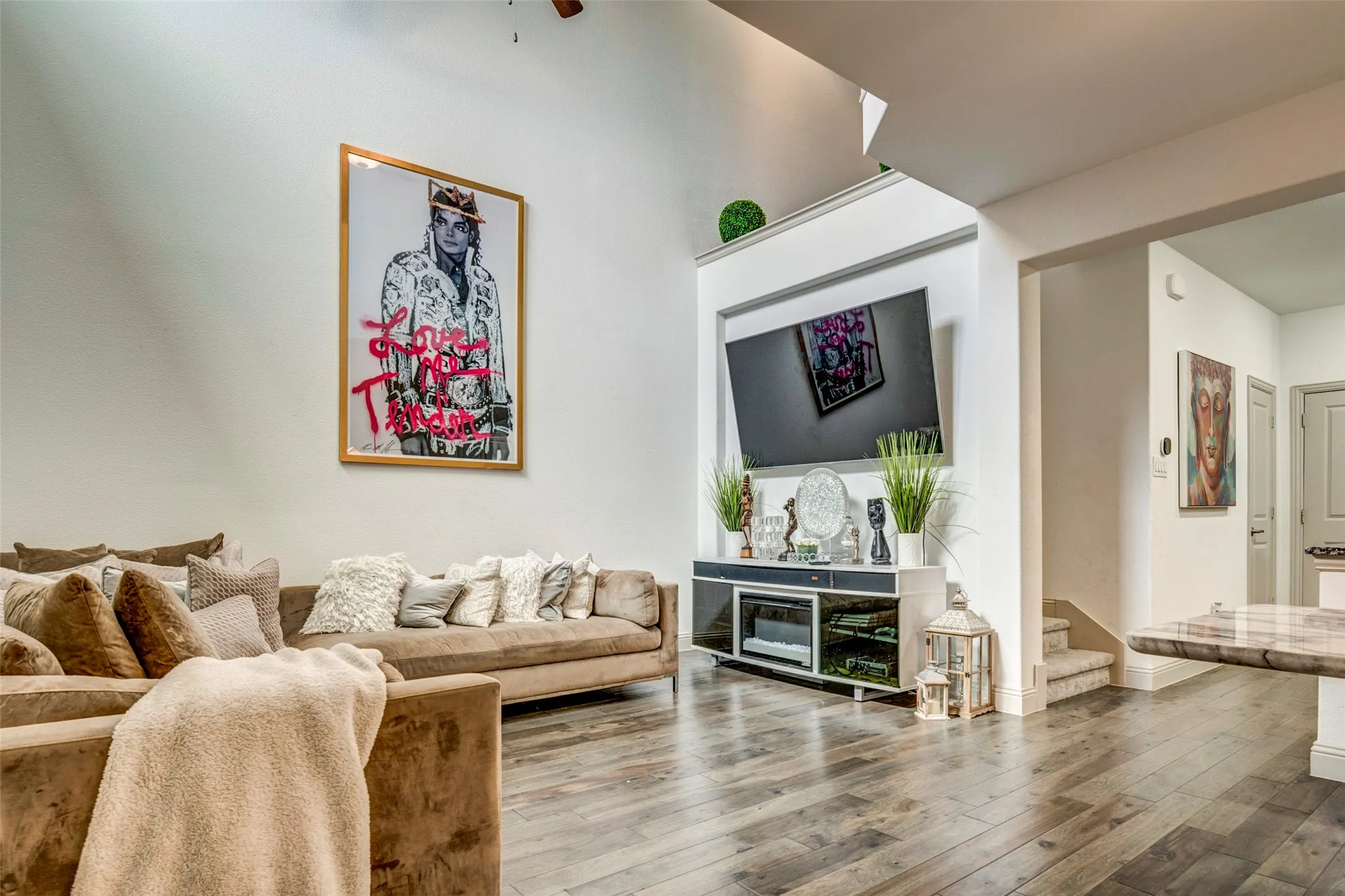 Spacious living area featuring high ceilings, wood-finish flooring, a built-in media console, a television niche, and a stone-top breakfast bar