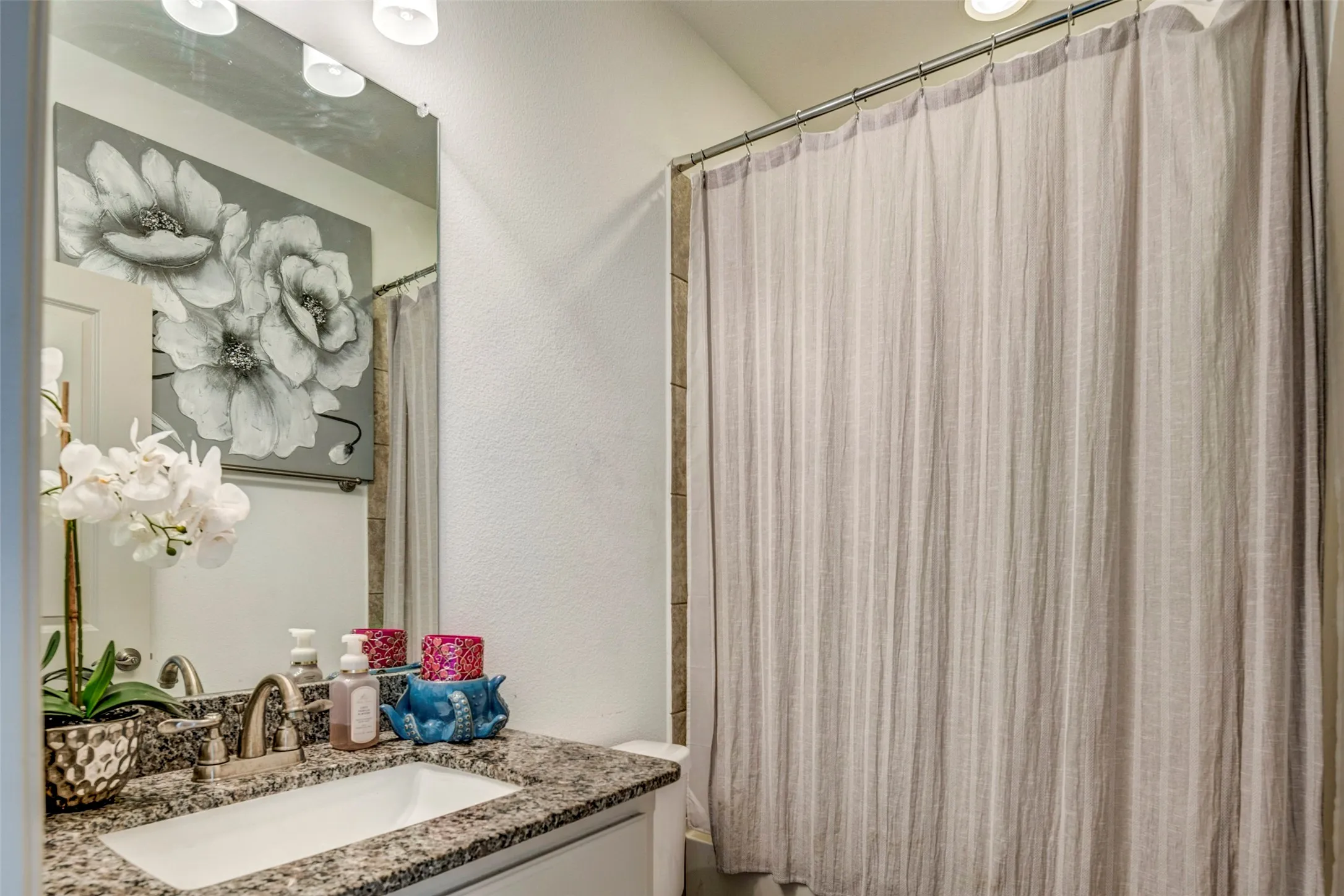Elegant bathroom featuring a granite-topped vanity with integrated sink, polished chrome fixtures, and ample counter space