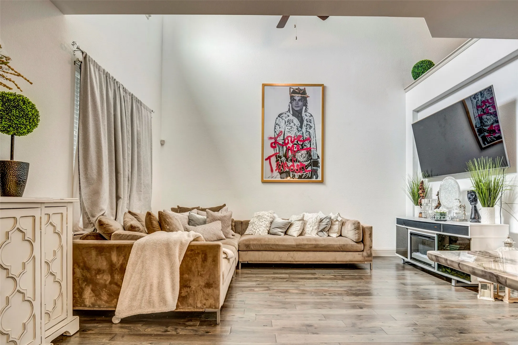 Spacious living area featuring high vaulted ceilings, light-toned walls, and wood-finish flooring