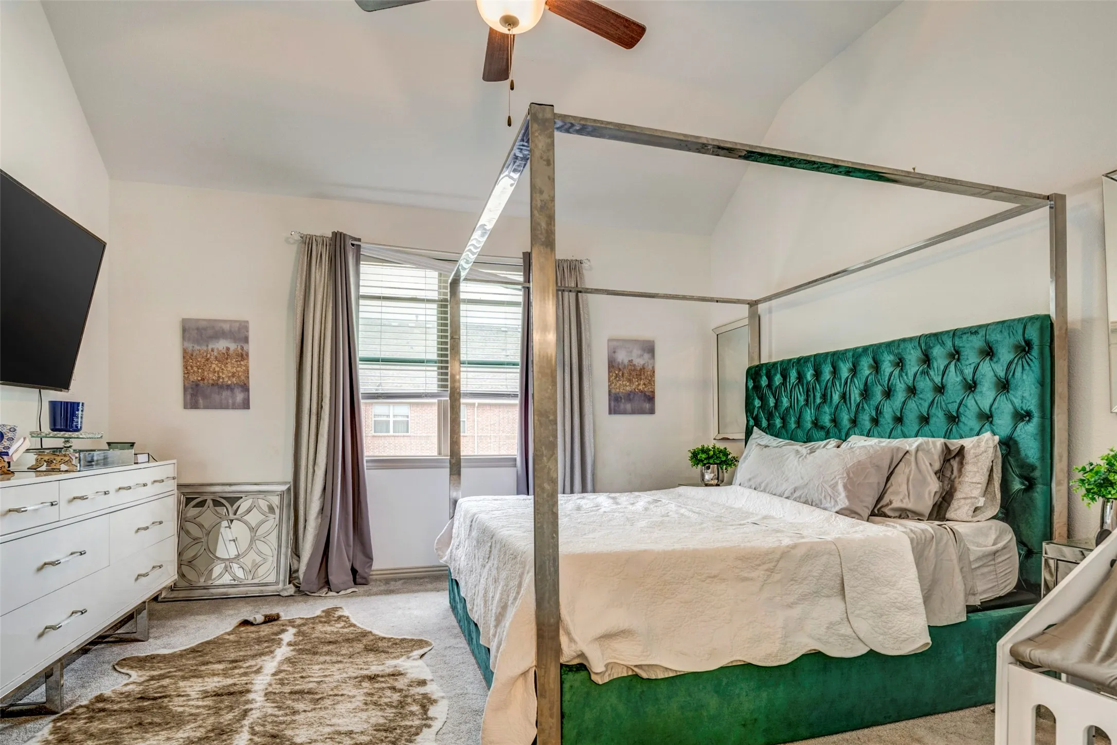 Vaulted ceilings enhance this space, featuring neutral carpeting and a ceiling fan