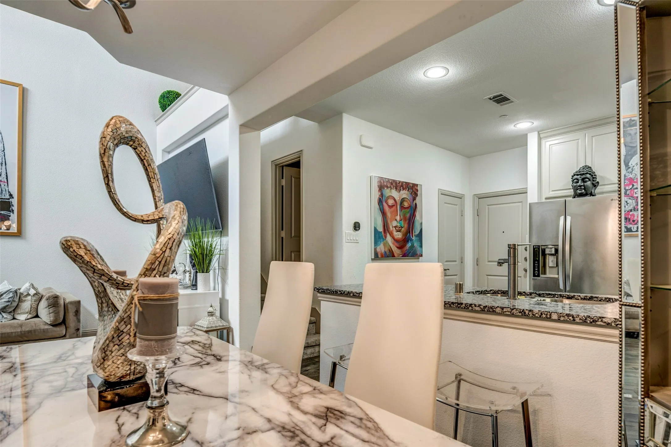Open-concept living space featuring a high ceiling, recessed lighting, a stainless steel refrigerator, and light-toned cabinetry