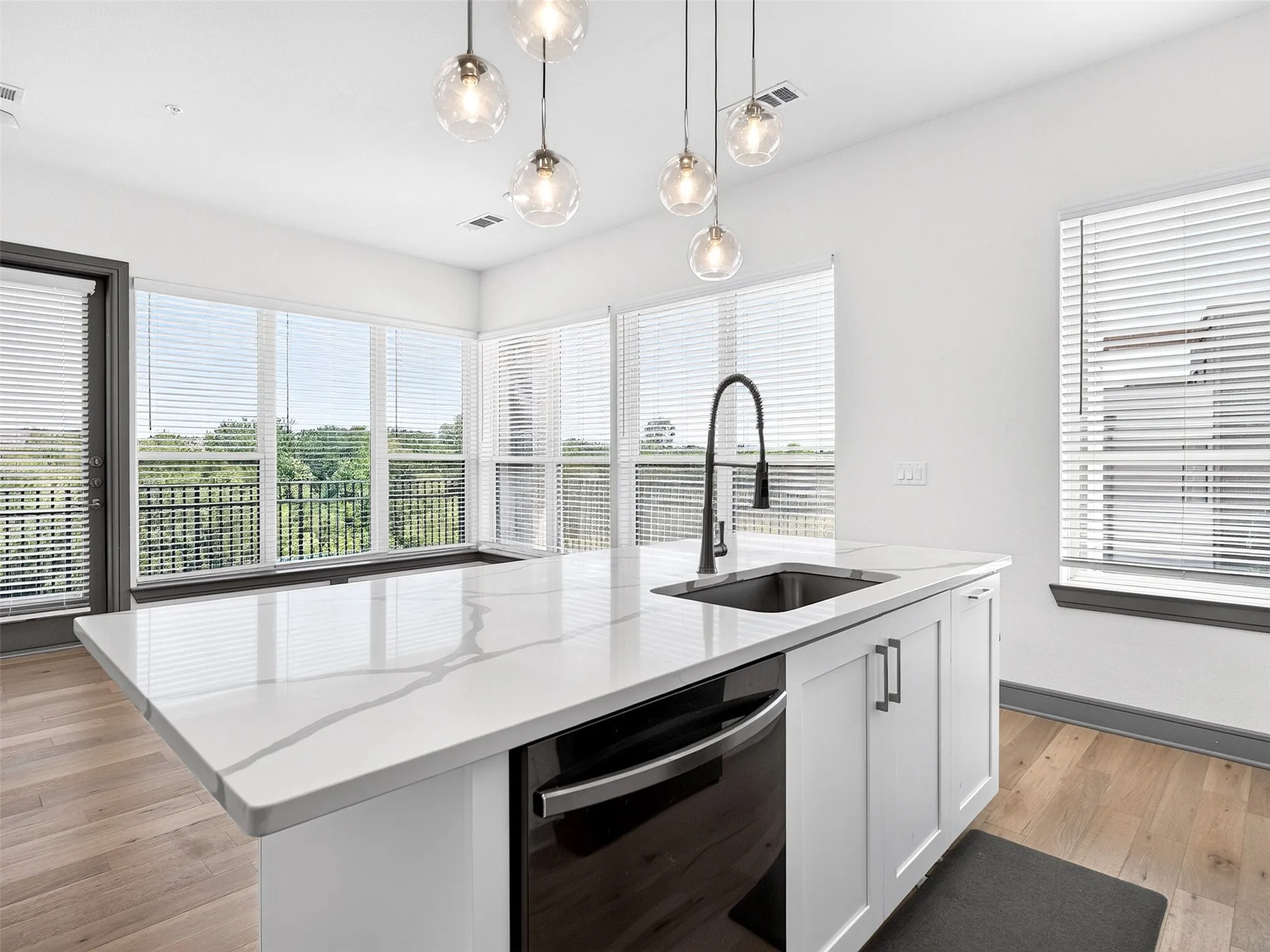 Kitchen island featuring a single-basin sink, matte black faucet, and white countertop with veining