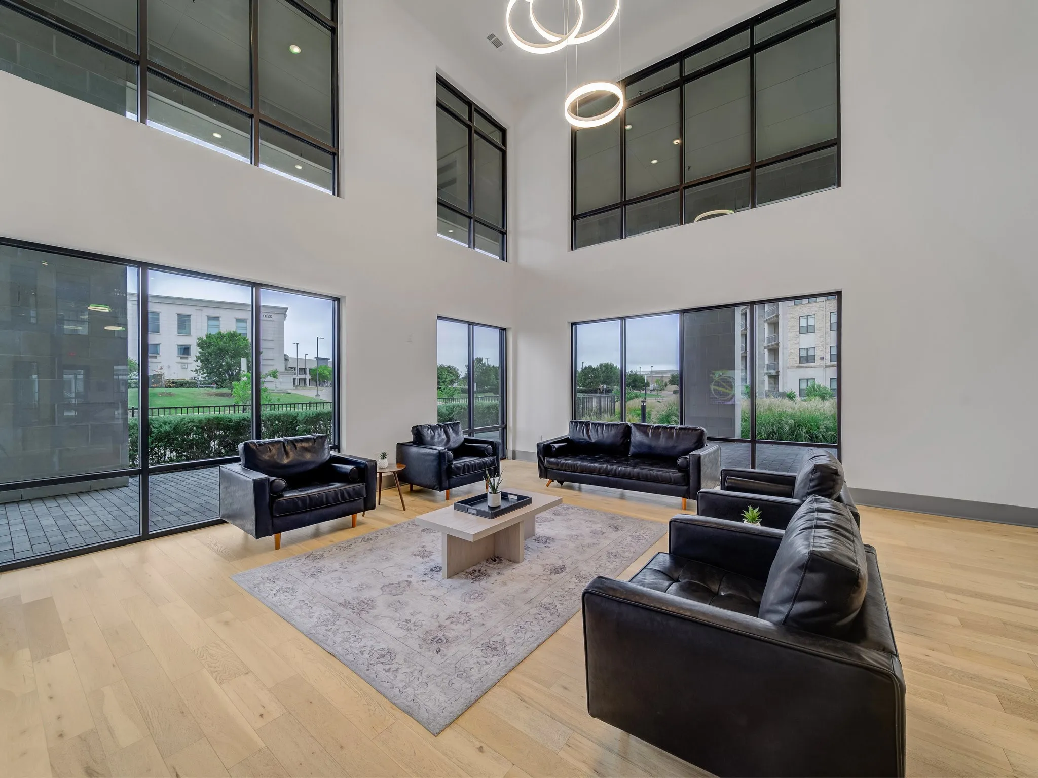 Soaring ceilings with tall windows, natural wood-finish flooring, recessed lighting, and modern pendant light fixtures