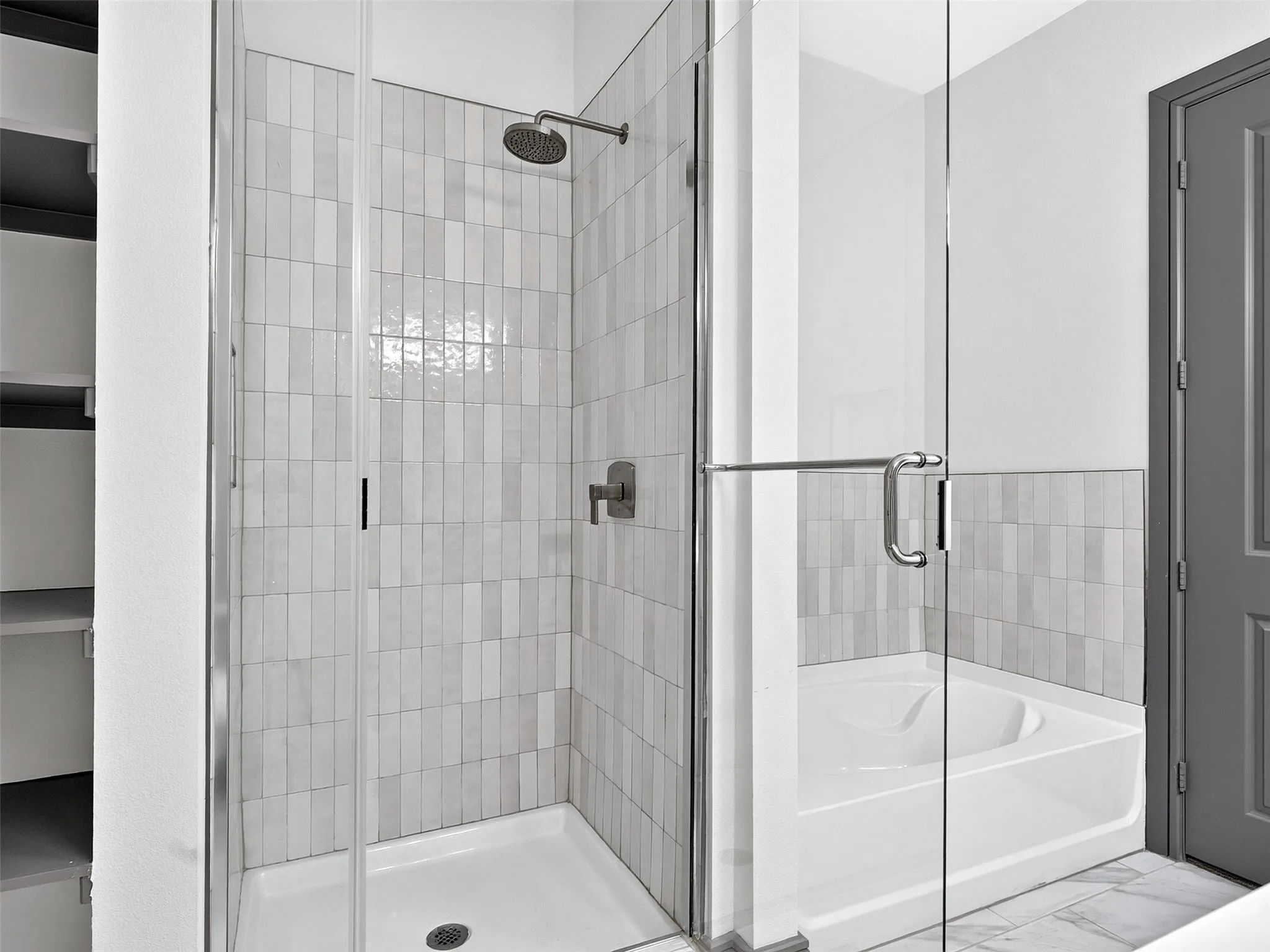 Glass-enclosed shower with a rainfall showerhead, and vertical tile surround