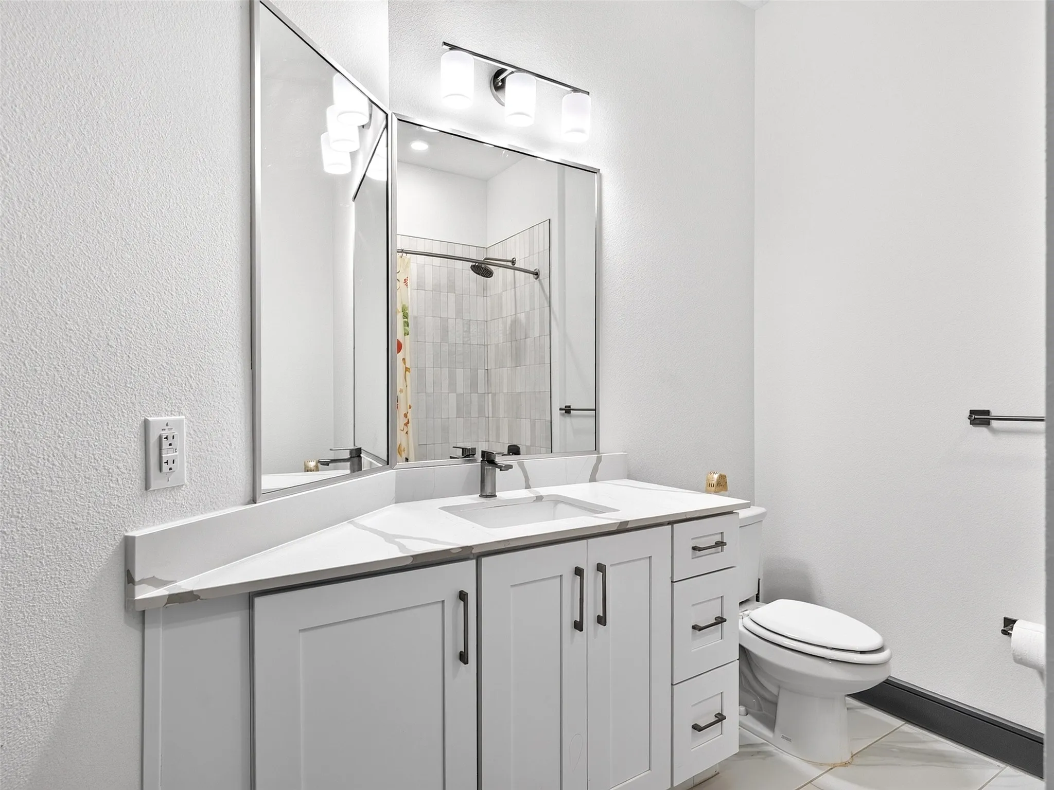 White shaker-style vanity with matte black hardware, dual undermount sinks, and a light-toned countertop