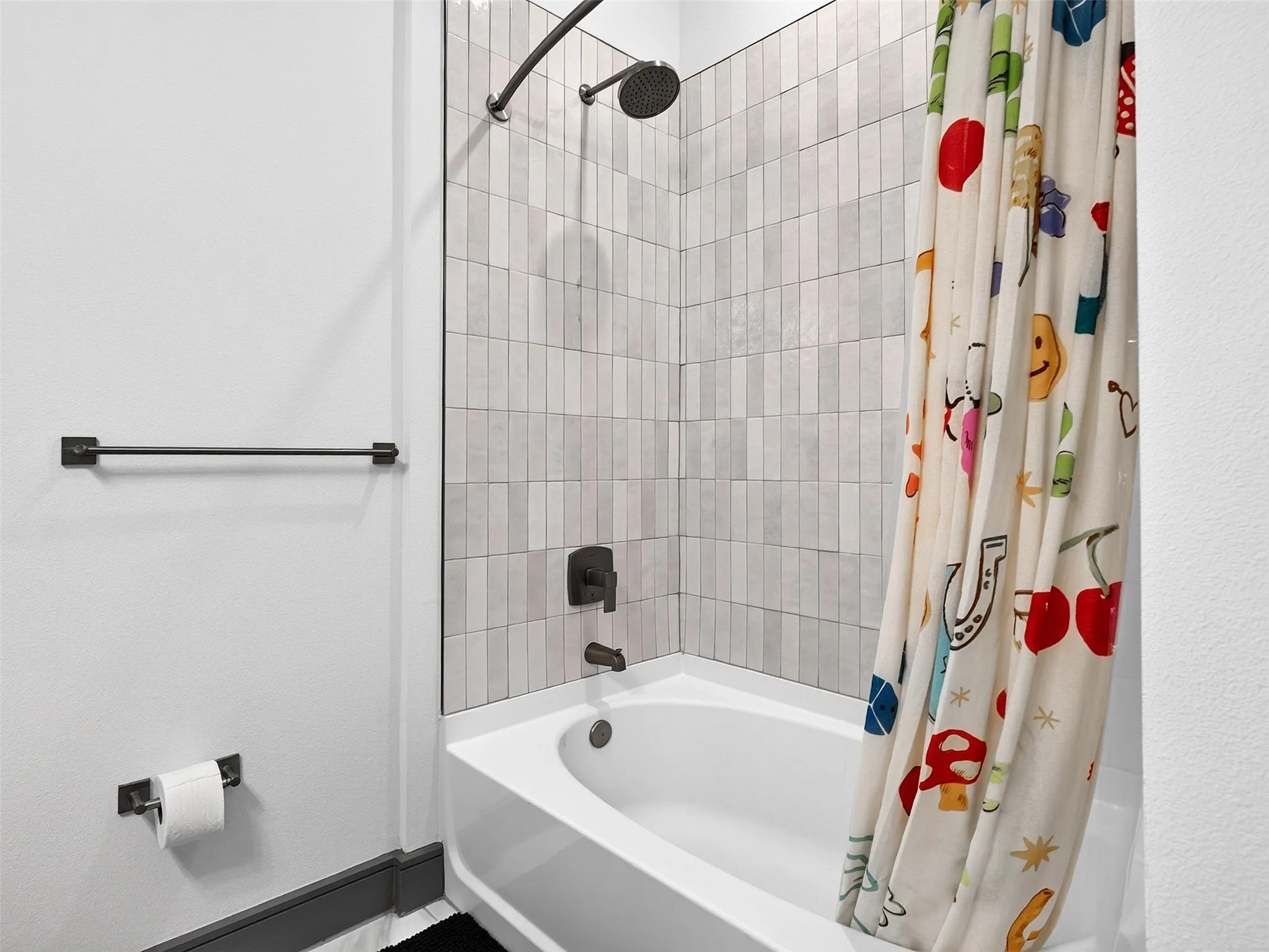 Shower and tub combination with vertical tile surround, matte black shower head, and matte black faucet