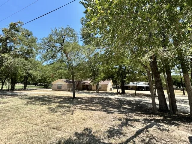 Another view of the front with mature trees, and circle drive.