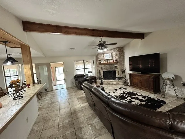 Living open to kitchen, dining with corner rock custom fireplace.