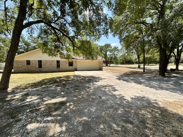Side view of the house with the two car garage and lots of shade from the beautiful mature trees.