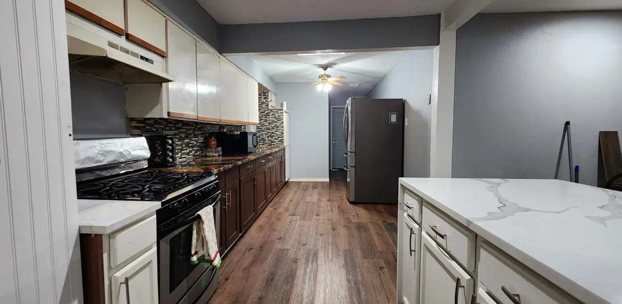 Kitchen featuring white upper cabinetry, dark wood lower cabinetry, dark stone countertops, tile backsplash, and wood-finish flooring