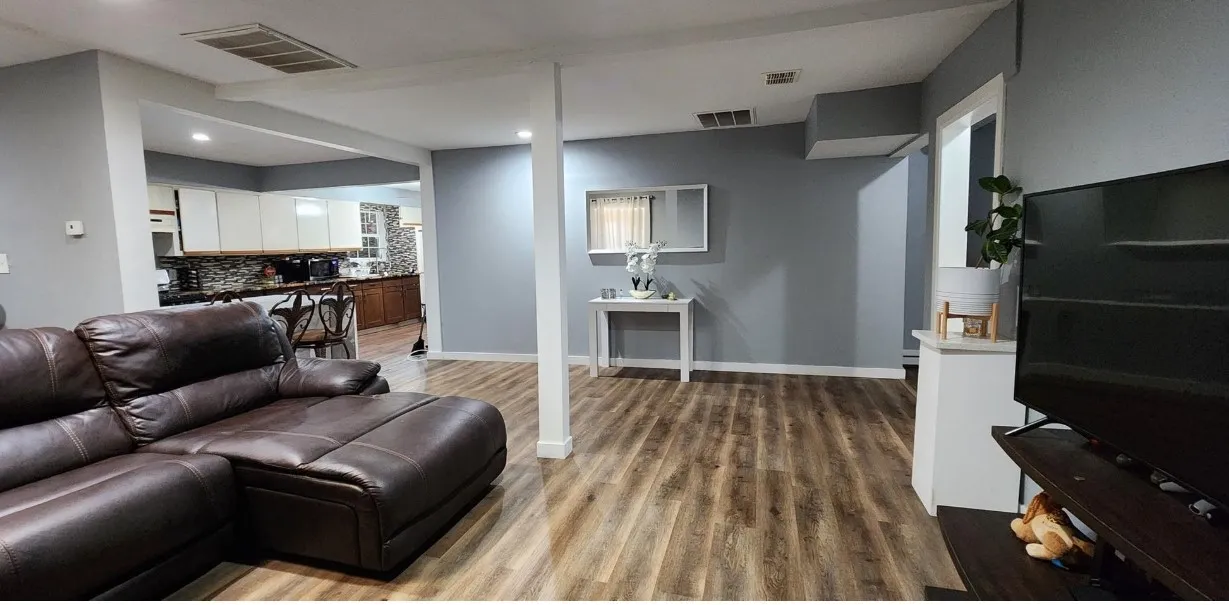 Wood-finish flooring throughout, light gray wall finishes, recessed ceiling lighting, and an open-concept layout