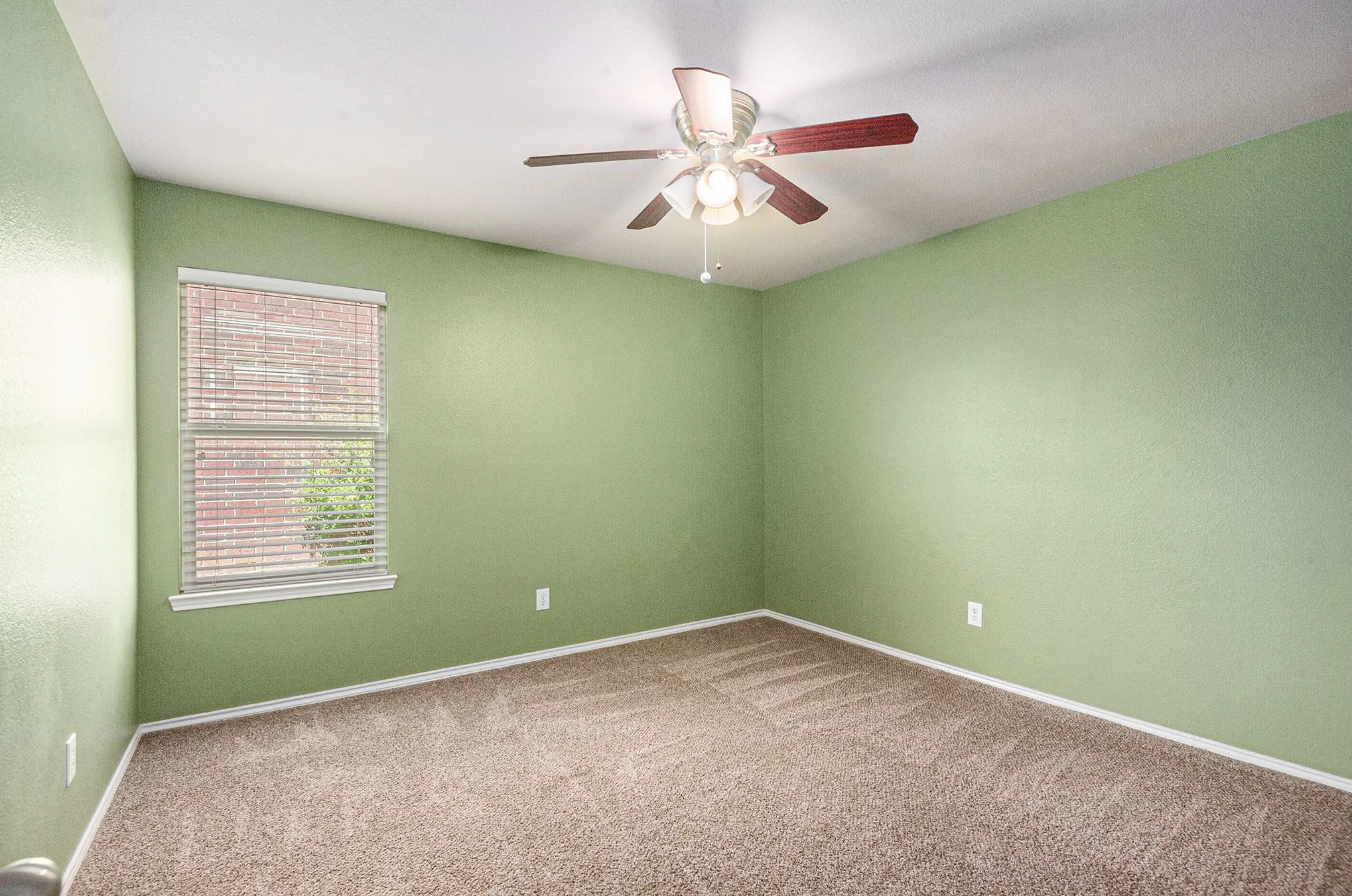 Carpeted empty room with baseboards and a ceiling fan