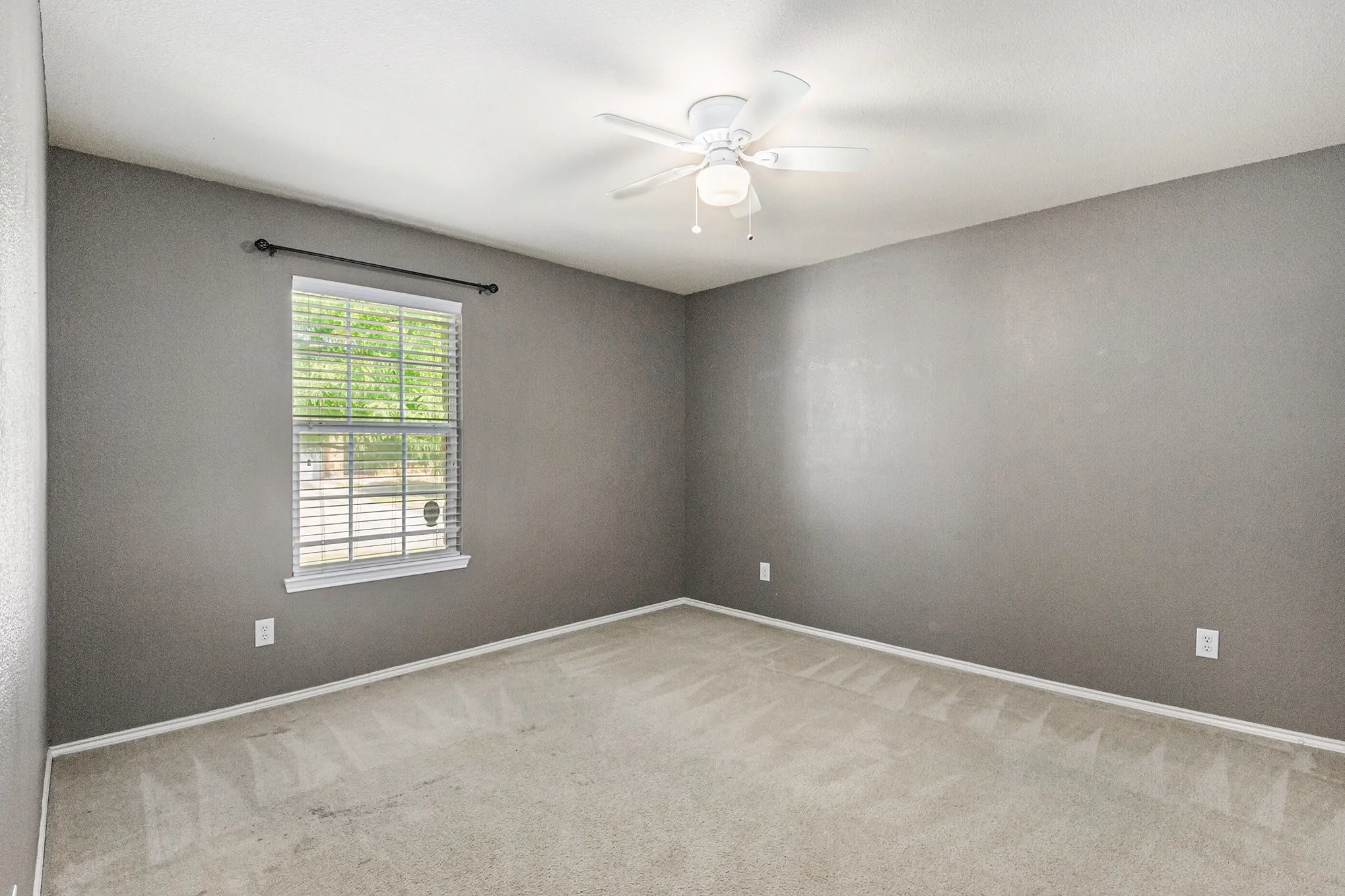 Spare room featuring light carpet and ceiling fan