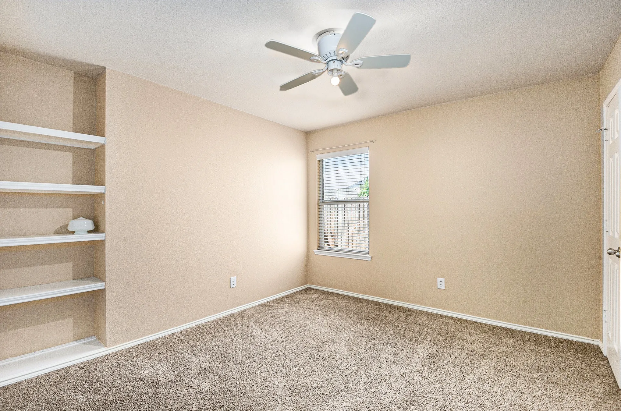 Empty room with light colored carpet and a ceiling fan